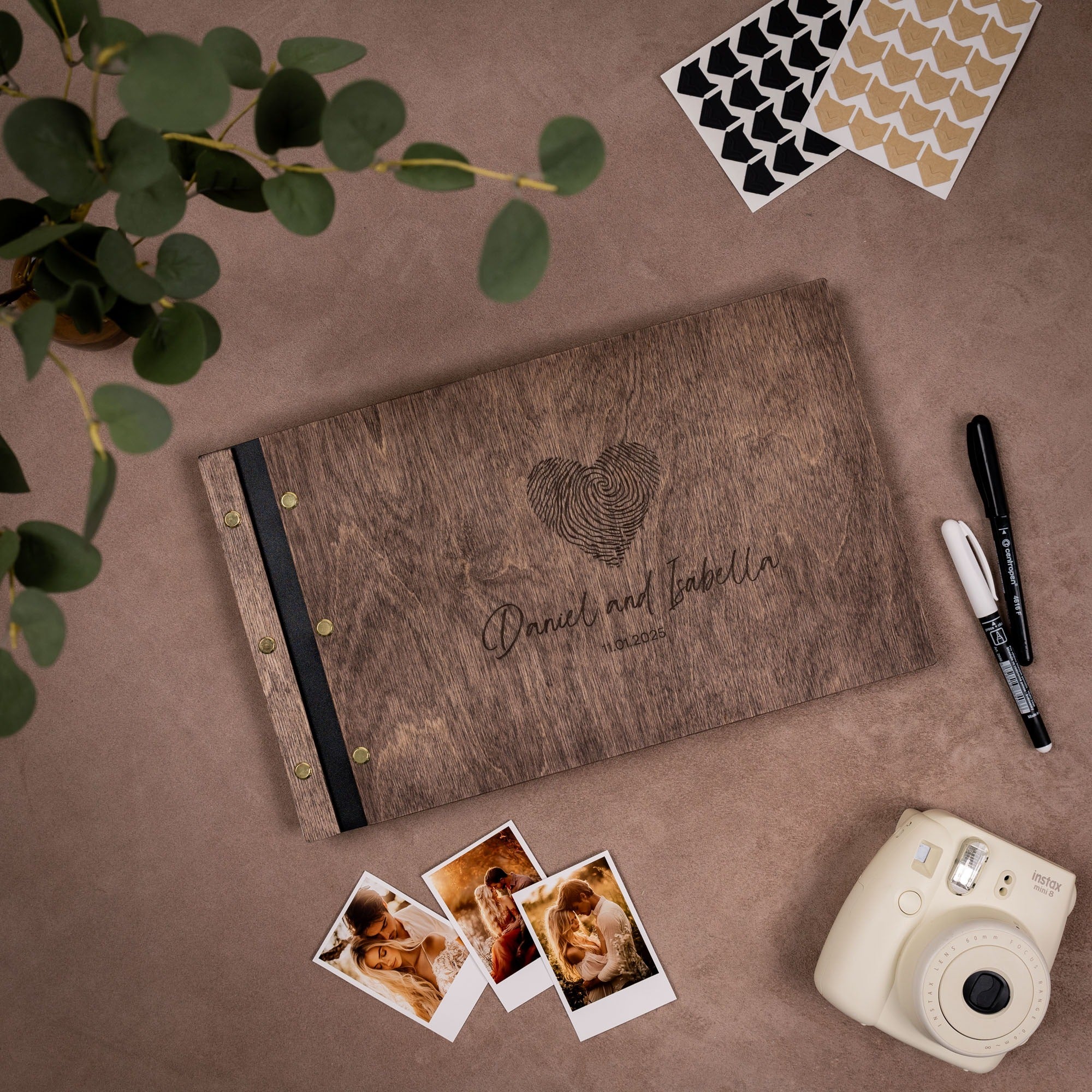 Wooden photo album with fingerprint design, photos, and camera on a brown surface