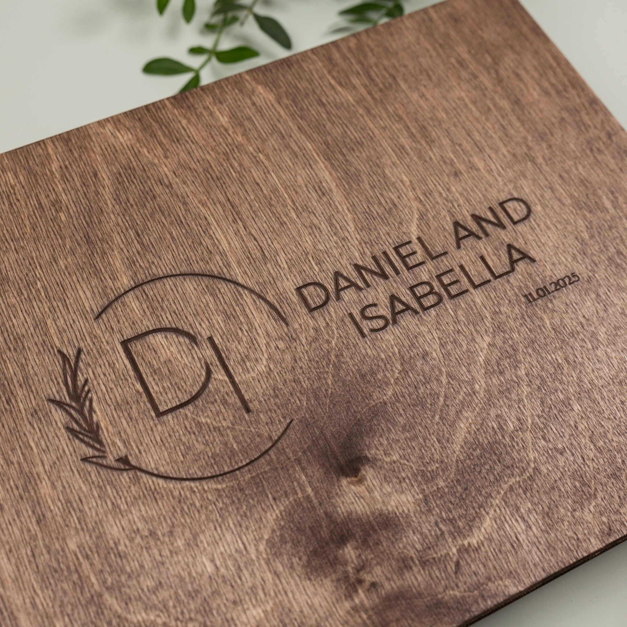 Wooden board with engraved initials 'DI' and names 'Daniel and Isabella' on a light background.