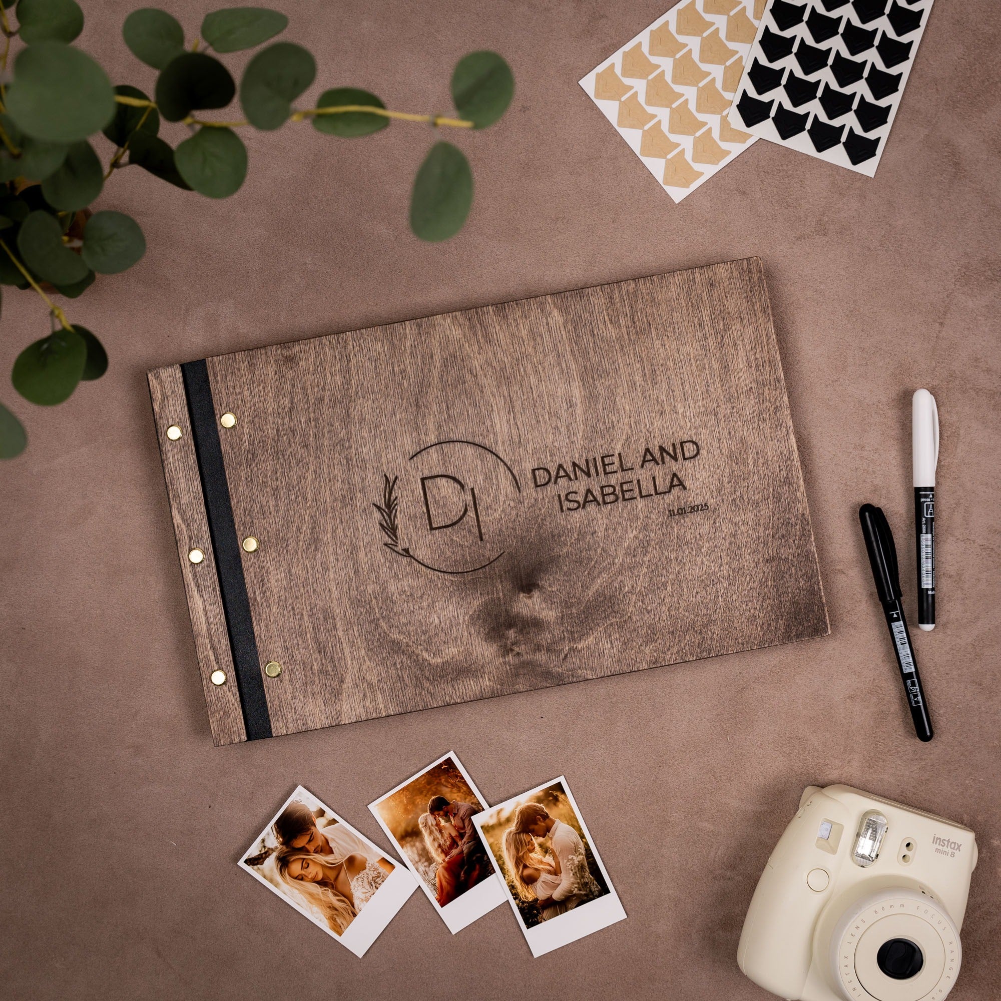 Personalized photo album with 'Daniel and Isabella' on a brown surface with photos and a camera.
