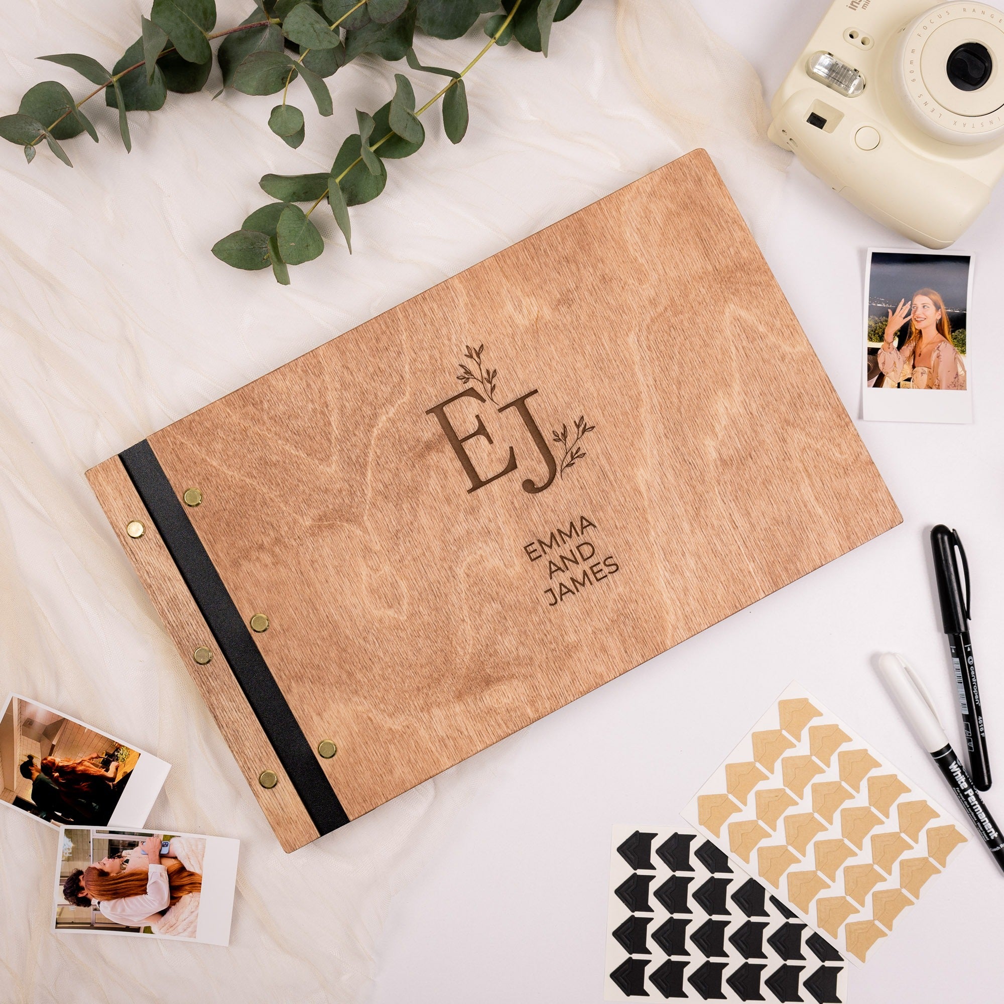Personalized photo album with 'EJ' initials on a white surface with photos and stationery items.