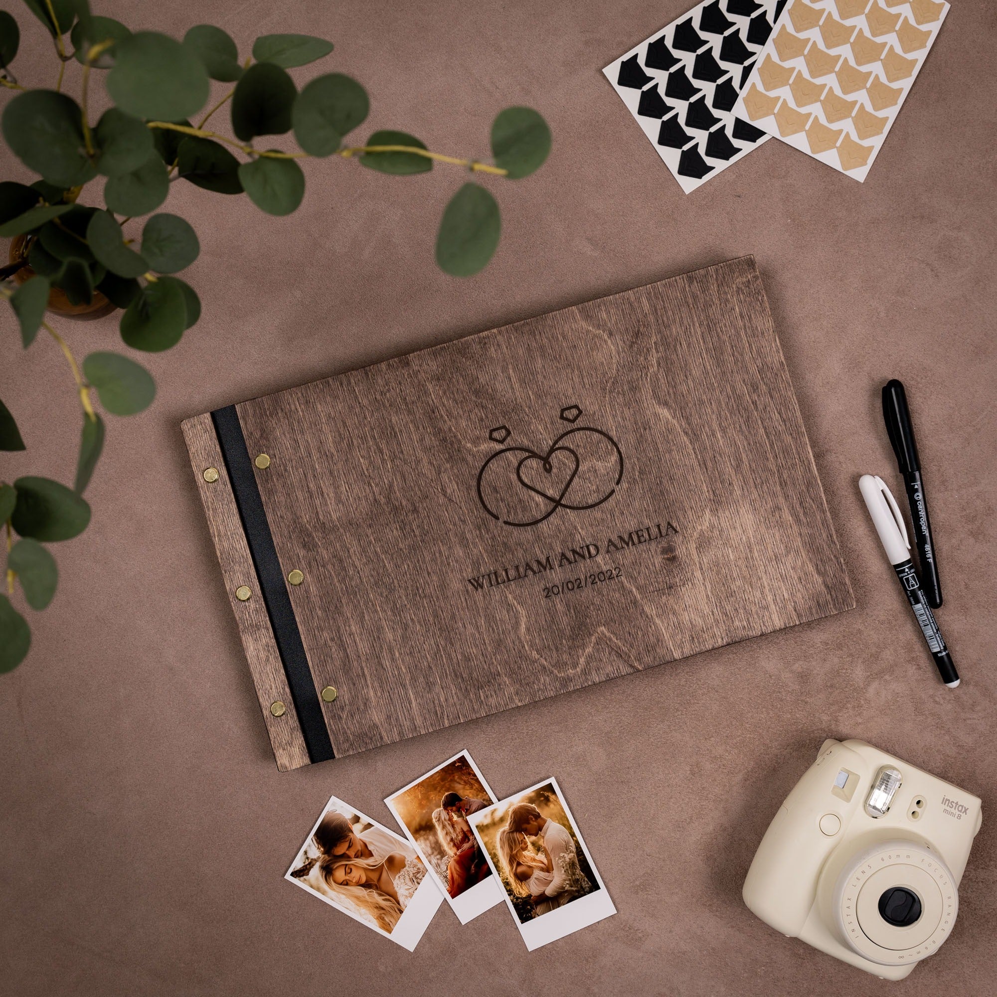Wooden photo album with engraved text, photos, and a camera on a brown surface.