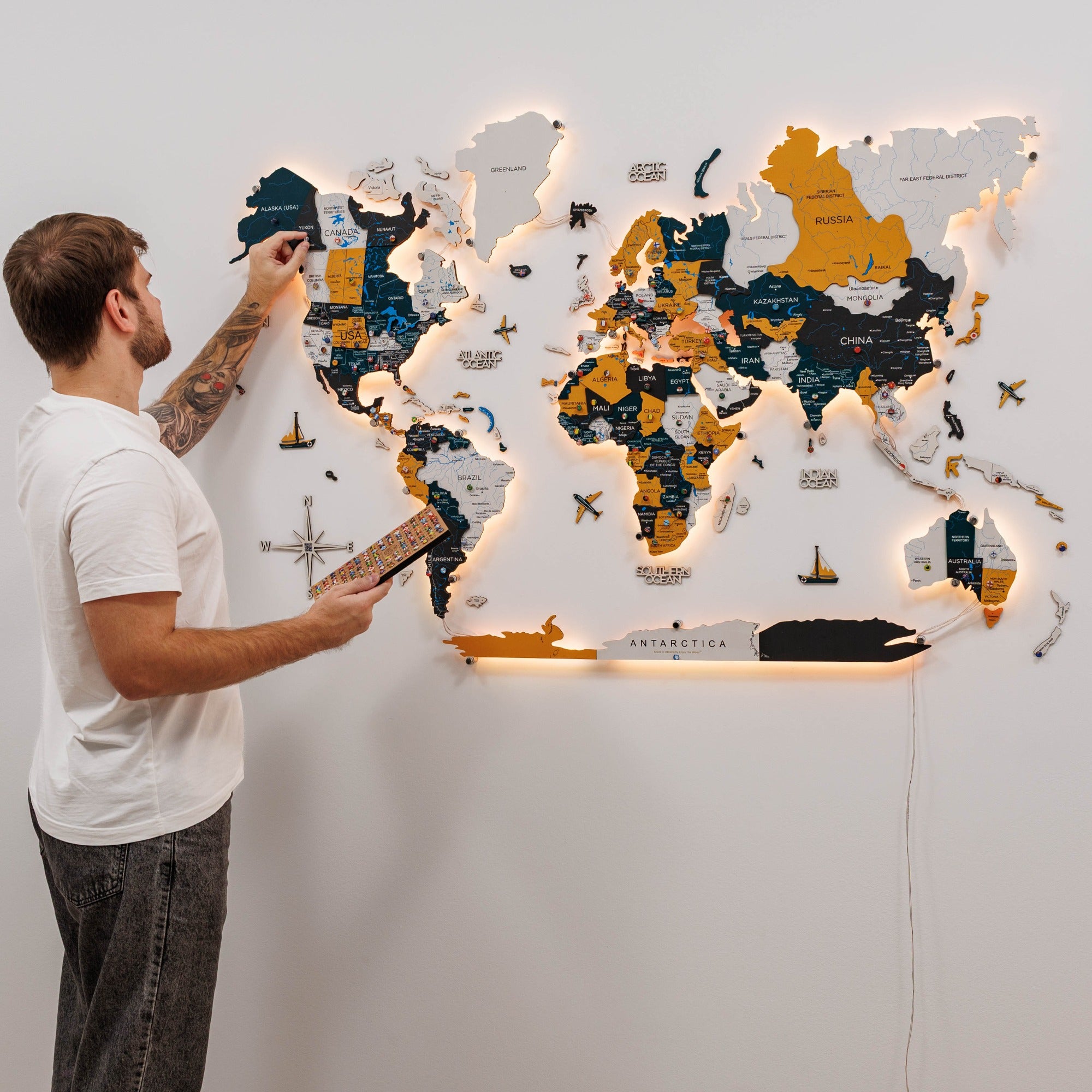 Man interacting with a world map on a wall, illuminated by lights.