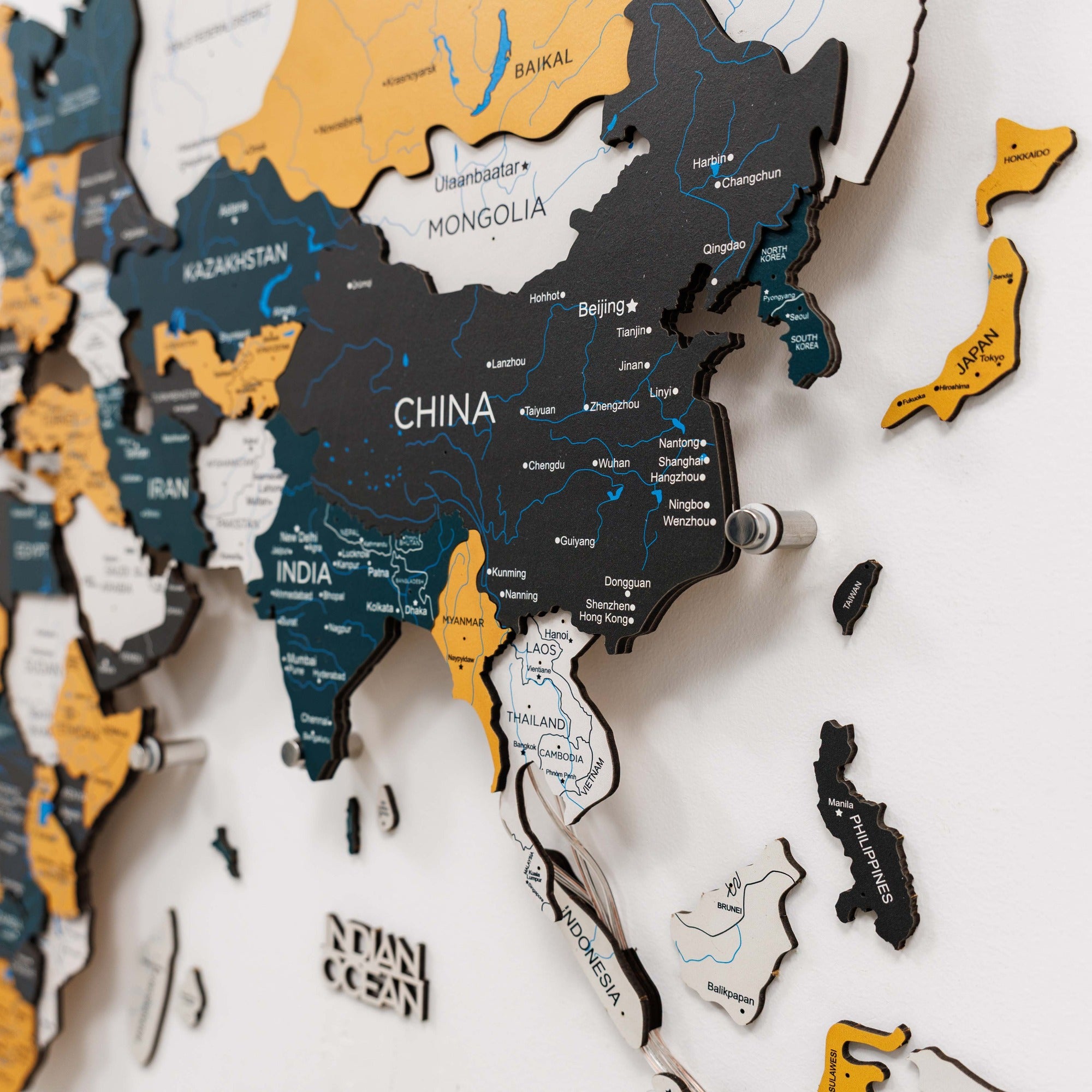 Wooden map of Asia with various countries cut out, displayed on a white background.