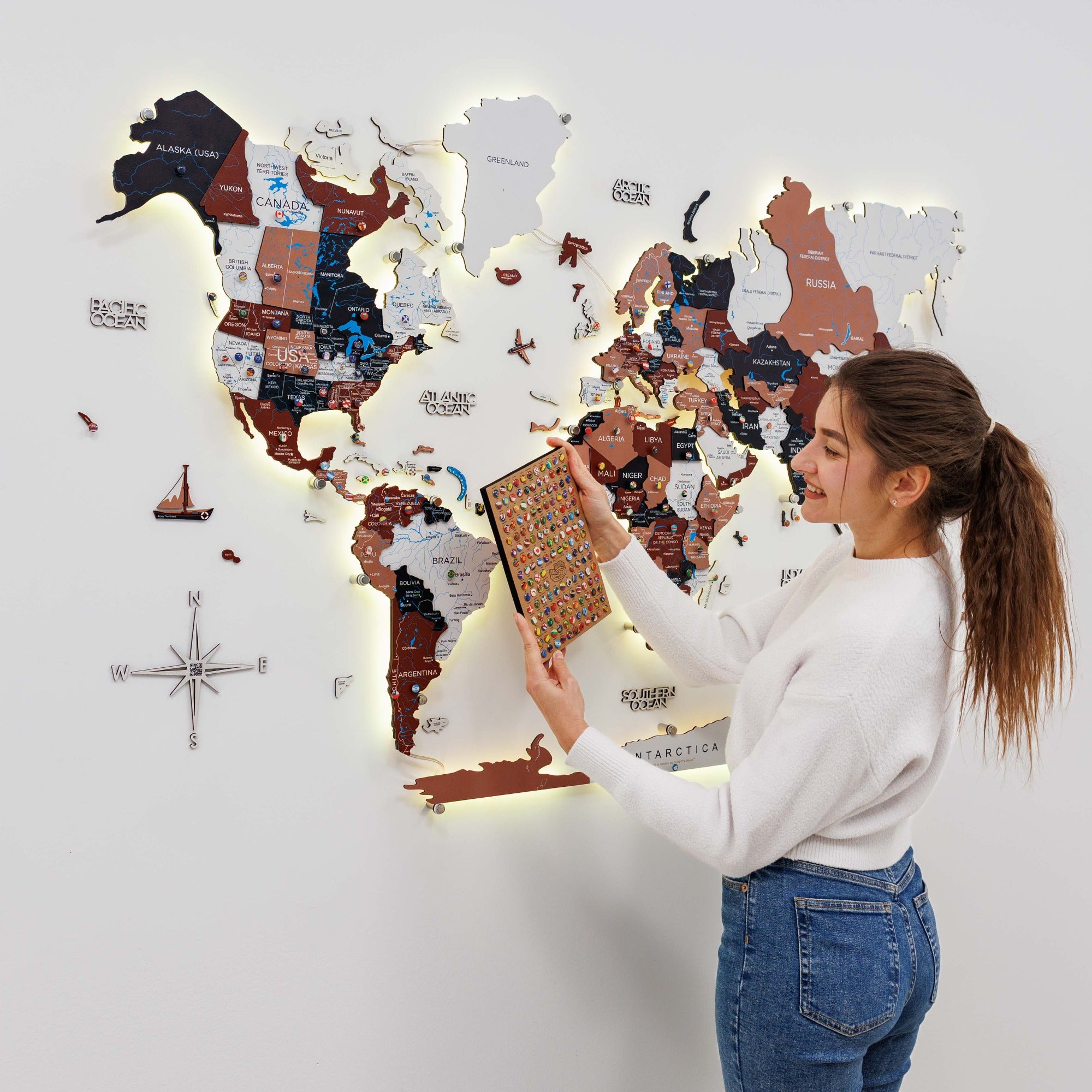 Woman interacting with a world map wall decoration on a light gray background