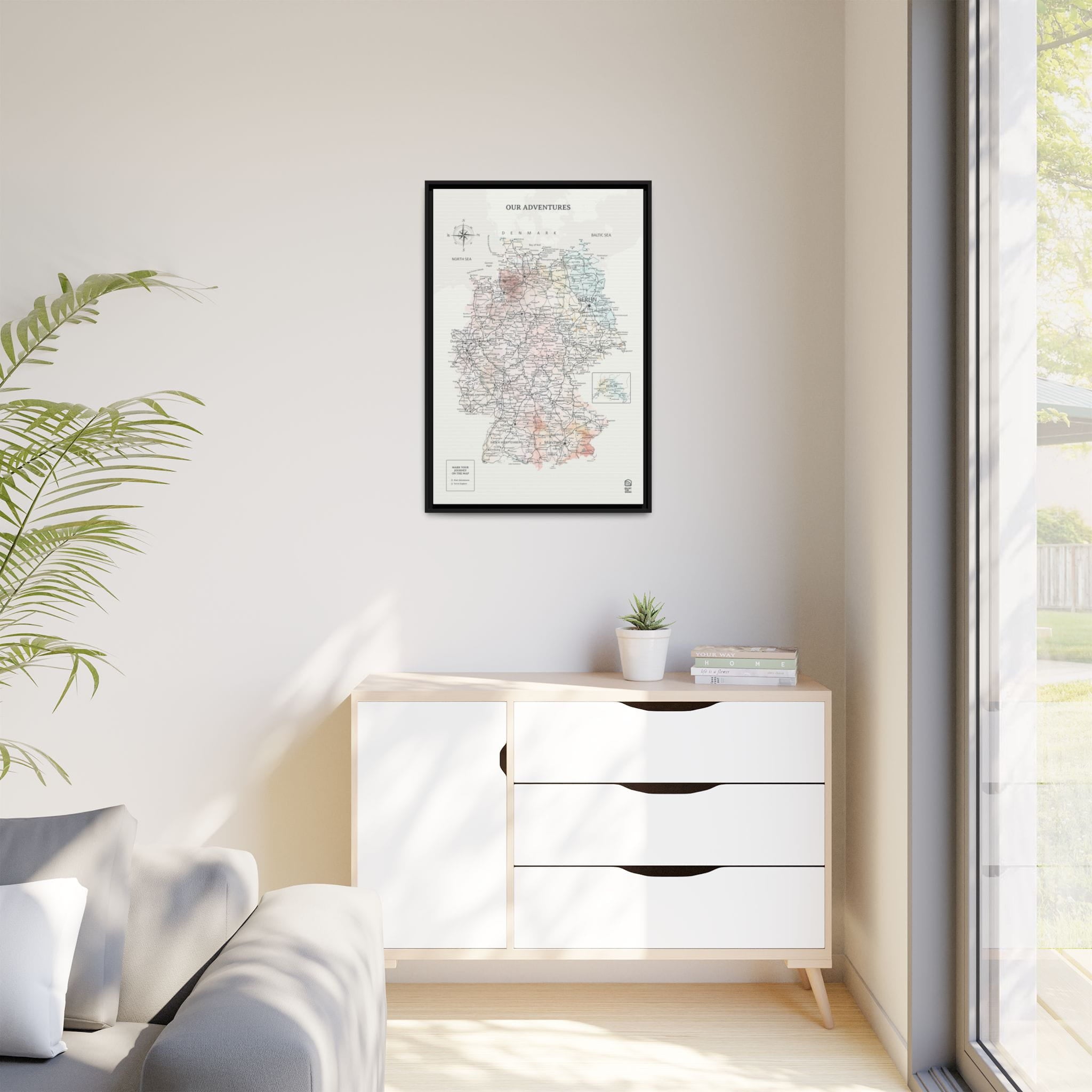 Modern living room with a white cabinet, framed map, and a plant.