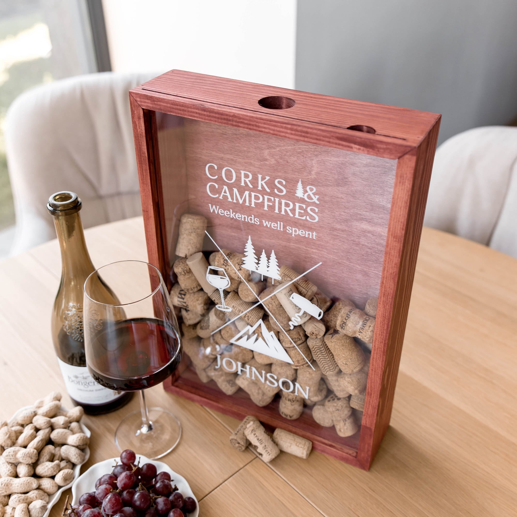 A personalized wooden gift box with a clear front panel filled with wine corks
