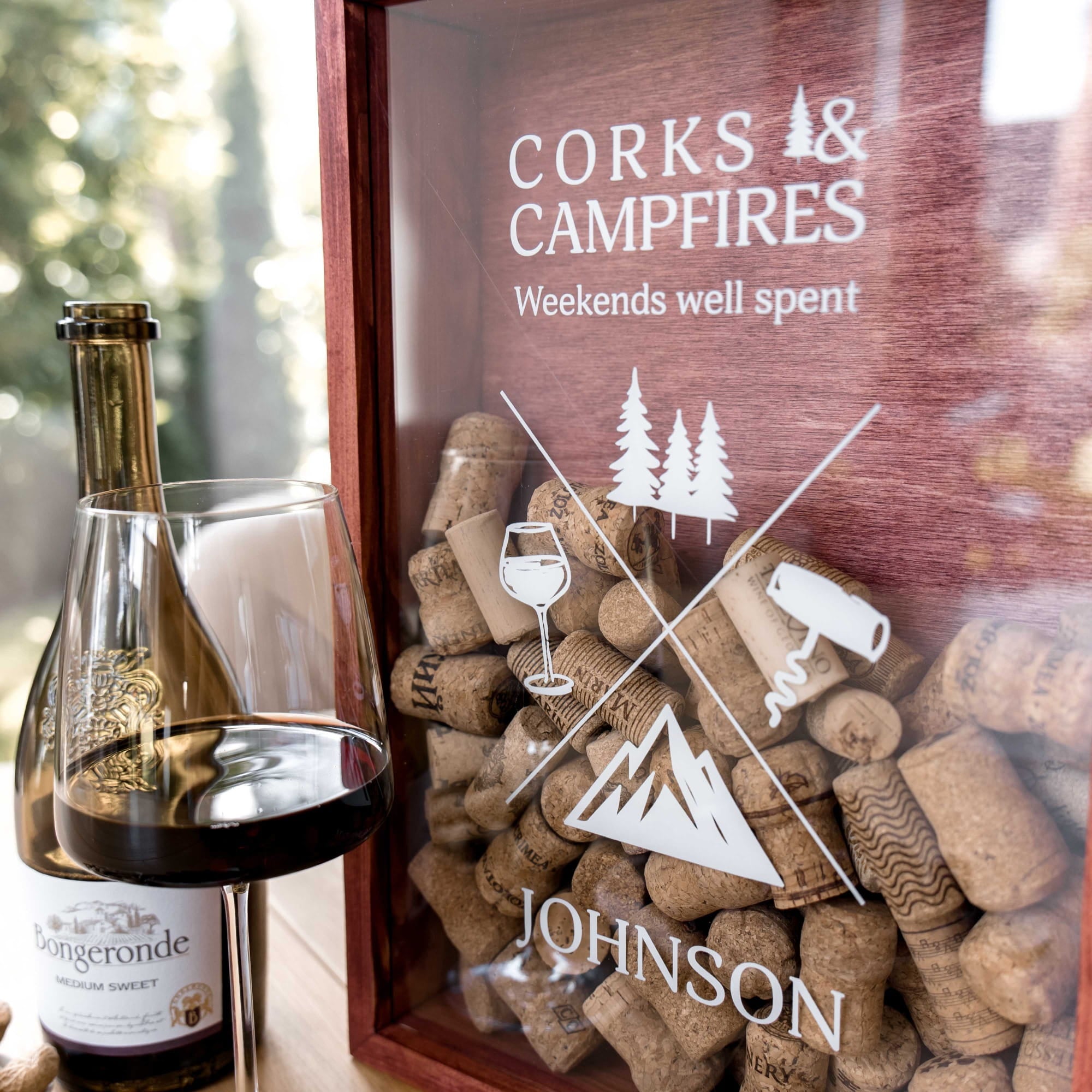 A personalized wooden wine cork display box with a glass front
