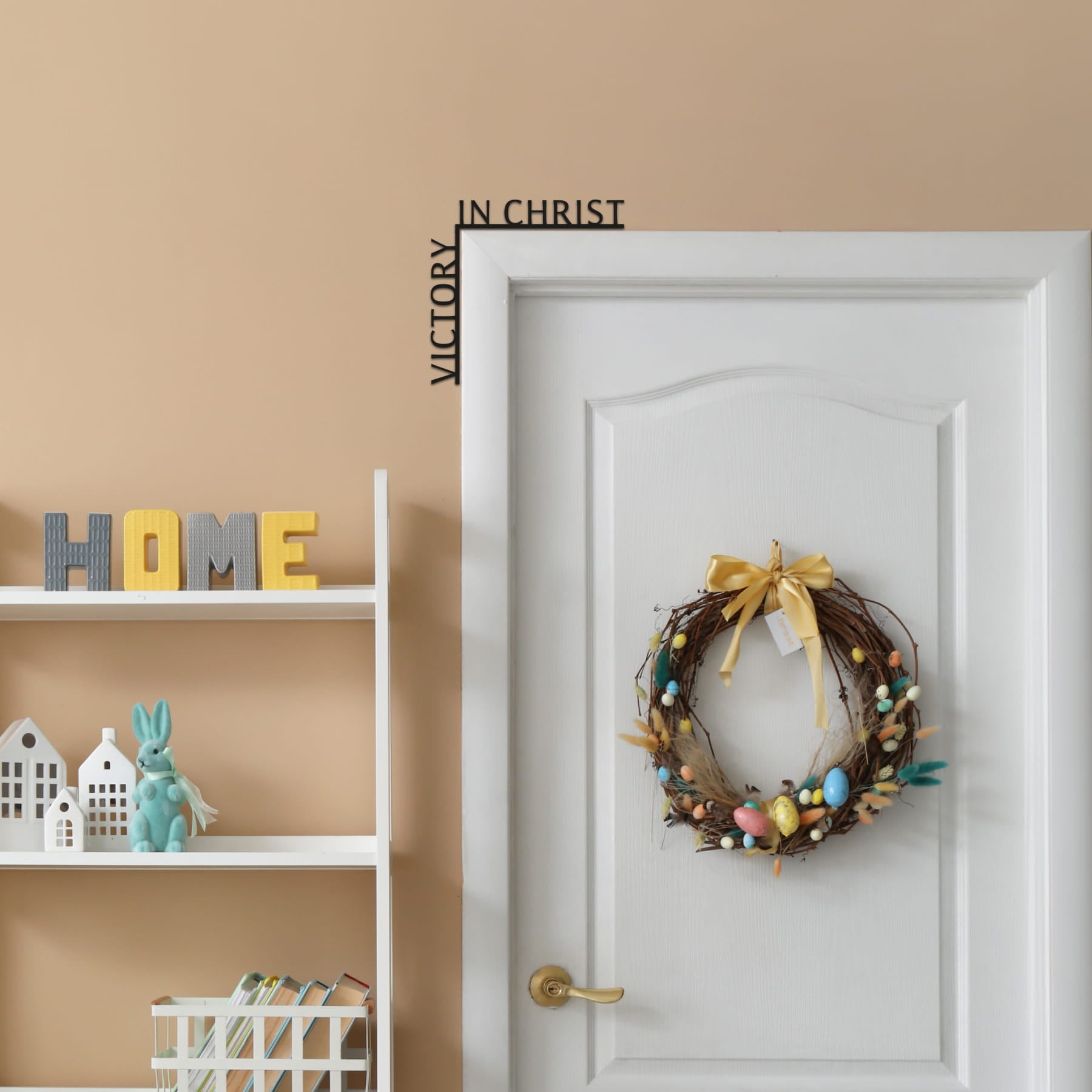 Decorative wreath on a door with 'HOME' sign and wall art in the background