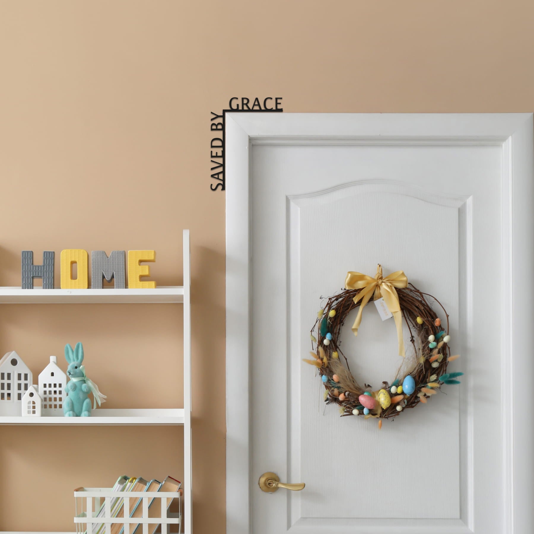 Decorative wreath on a white door with 'HOME' sign and shelf in the background.