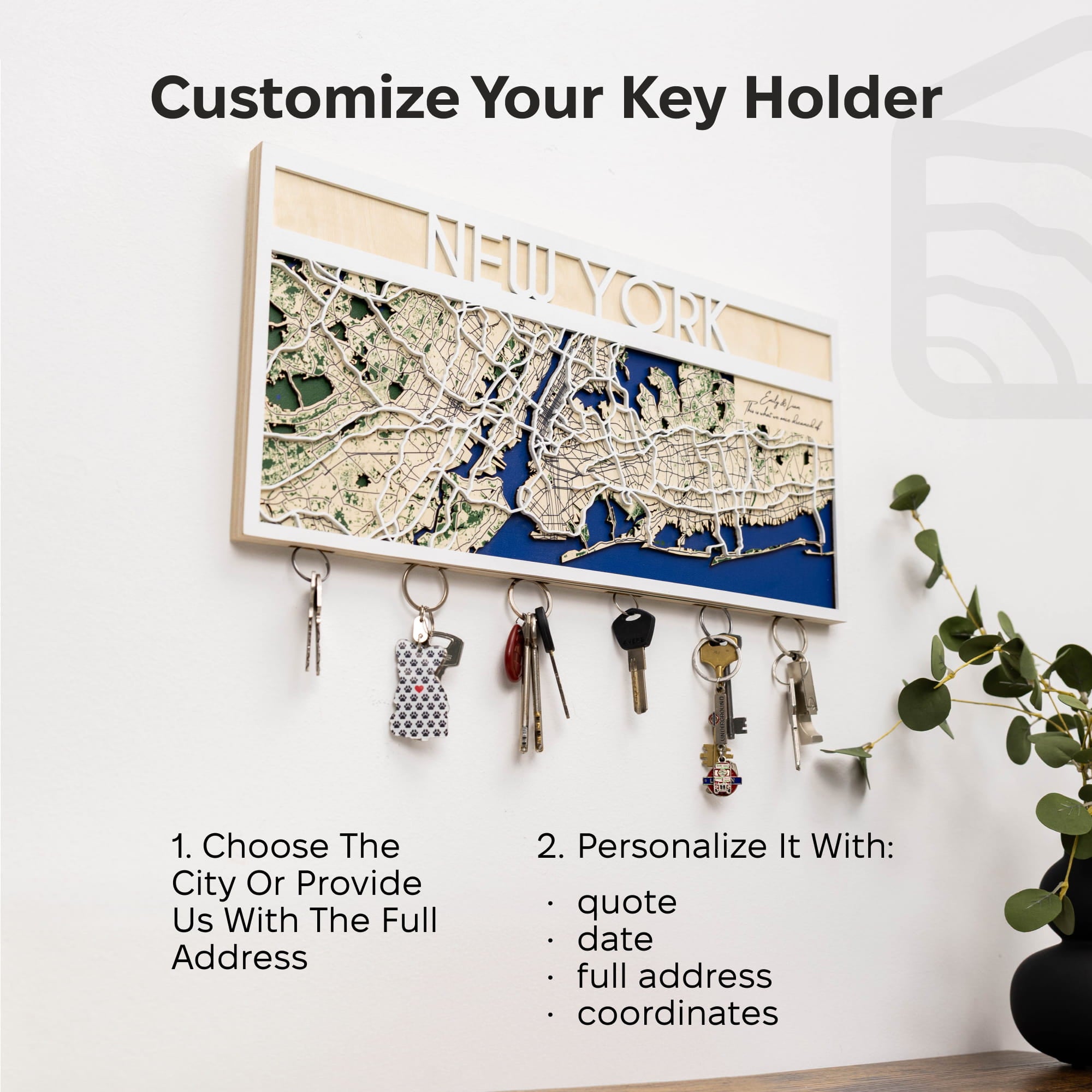 Key holder with map design of New York, keys hanging from it, on a white wall.