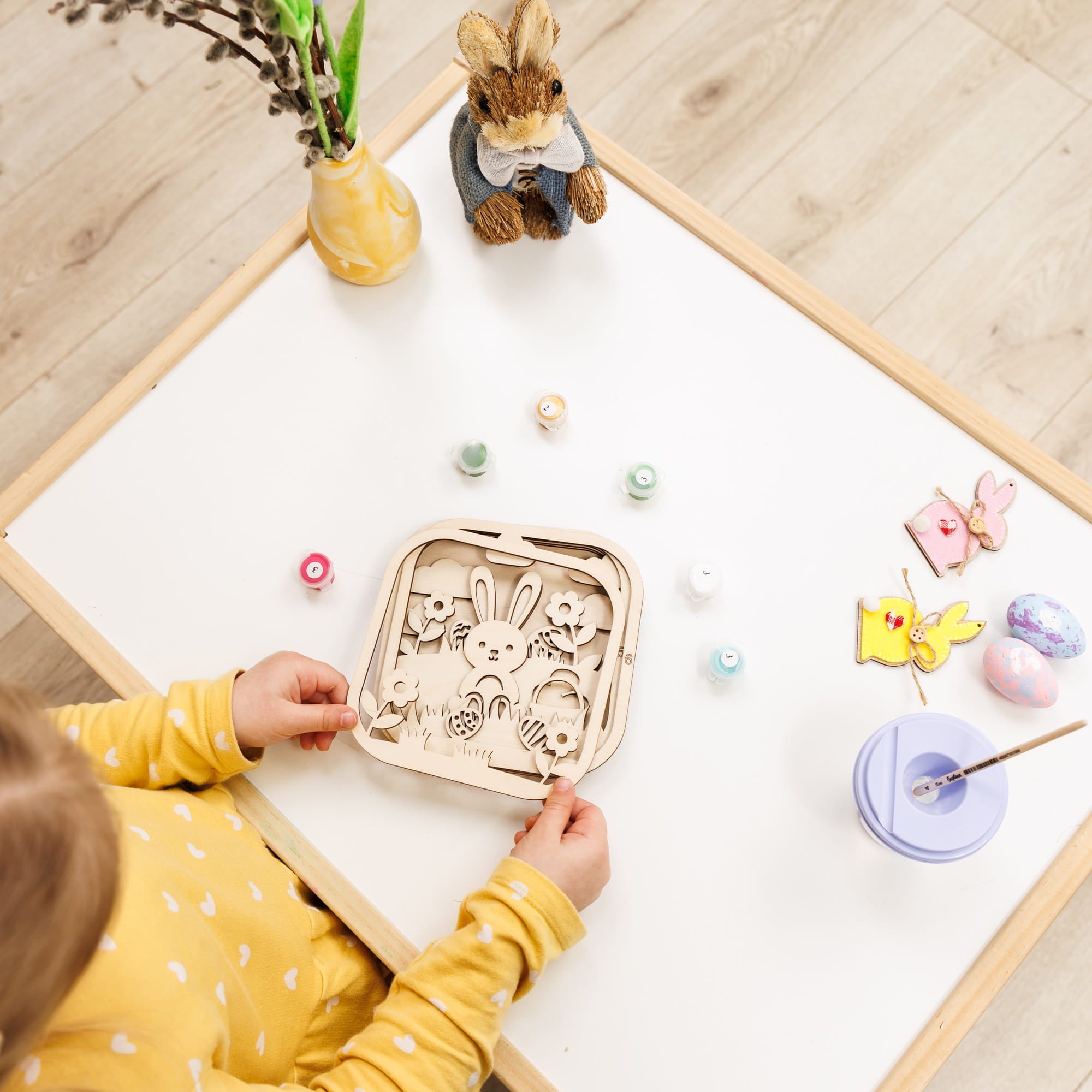 Child playing with a wooden toy on a light-colored surface