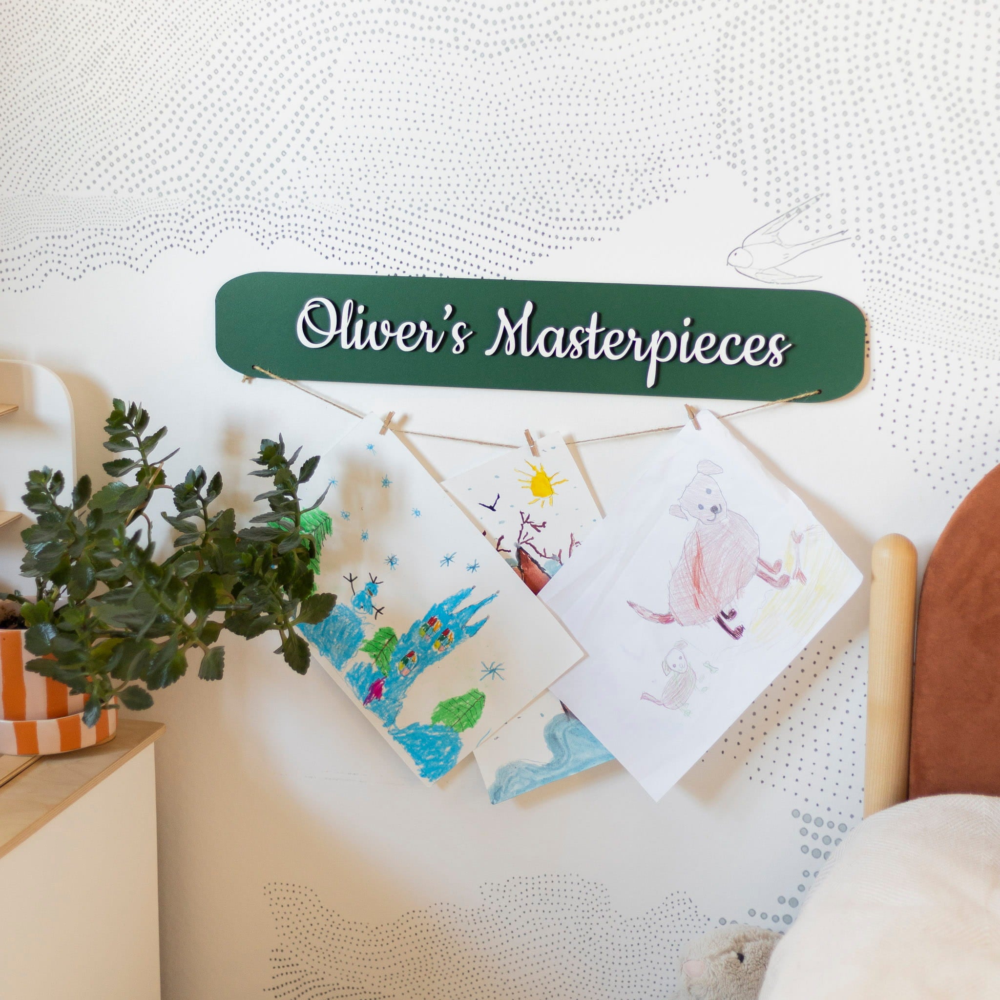 Children's drawings on a wall with 'Oliver's Masterpieces' sign