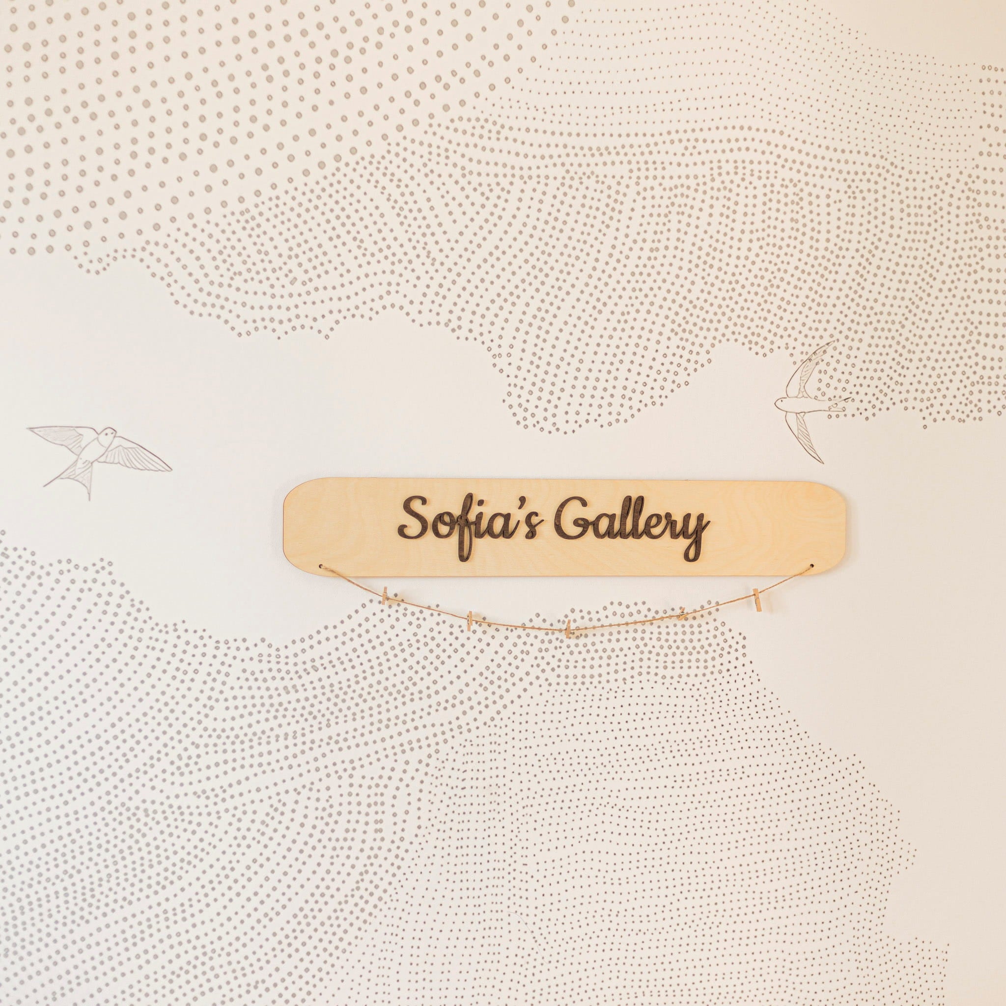 Wooden sign with 'Sofia's Gallery' on a textured beige background