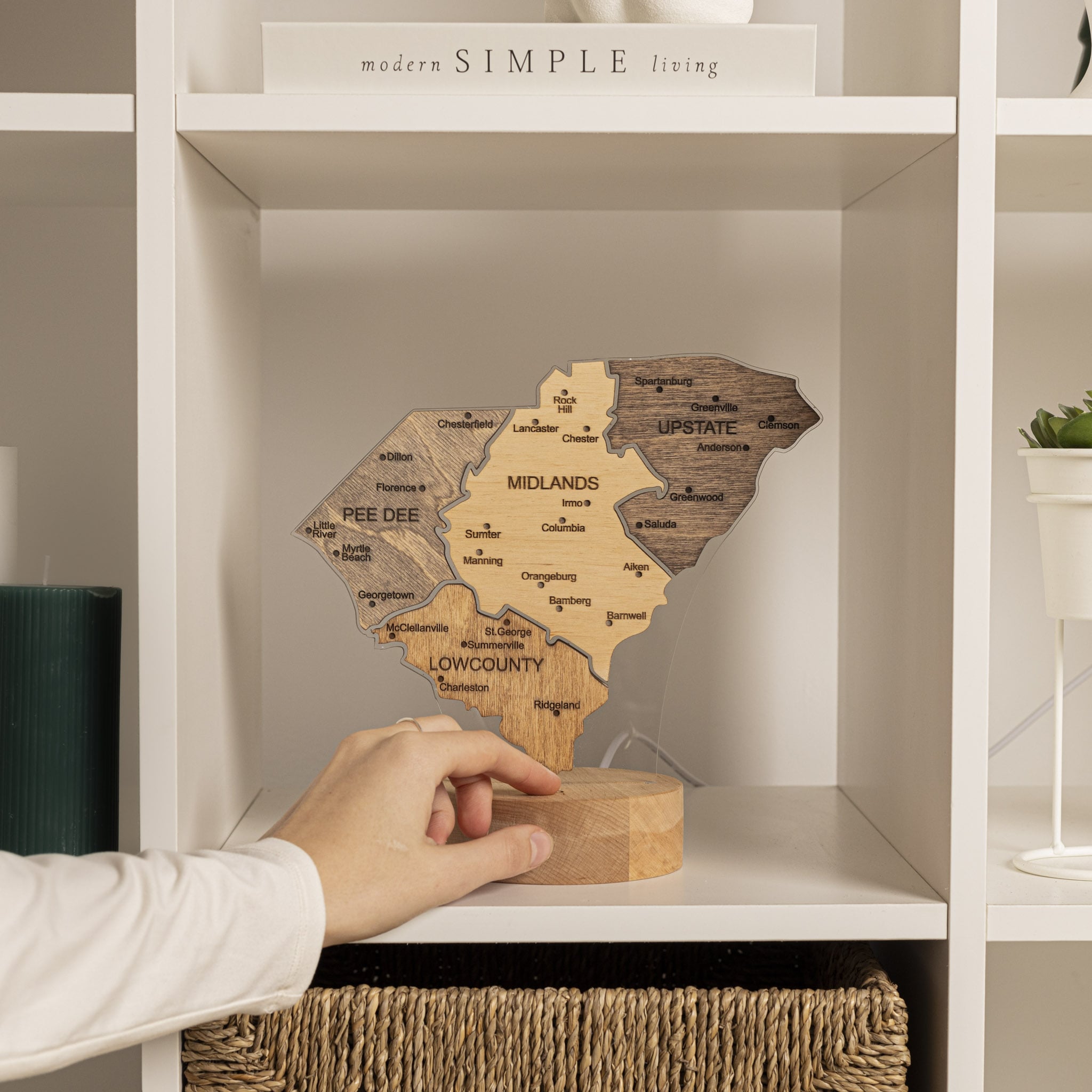 Wooden map of a region on a shelf with a hand reaching out