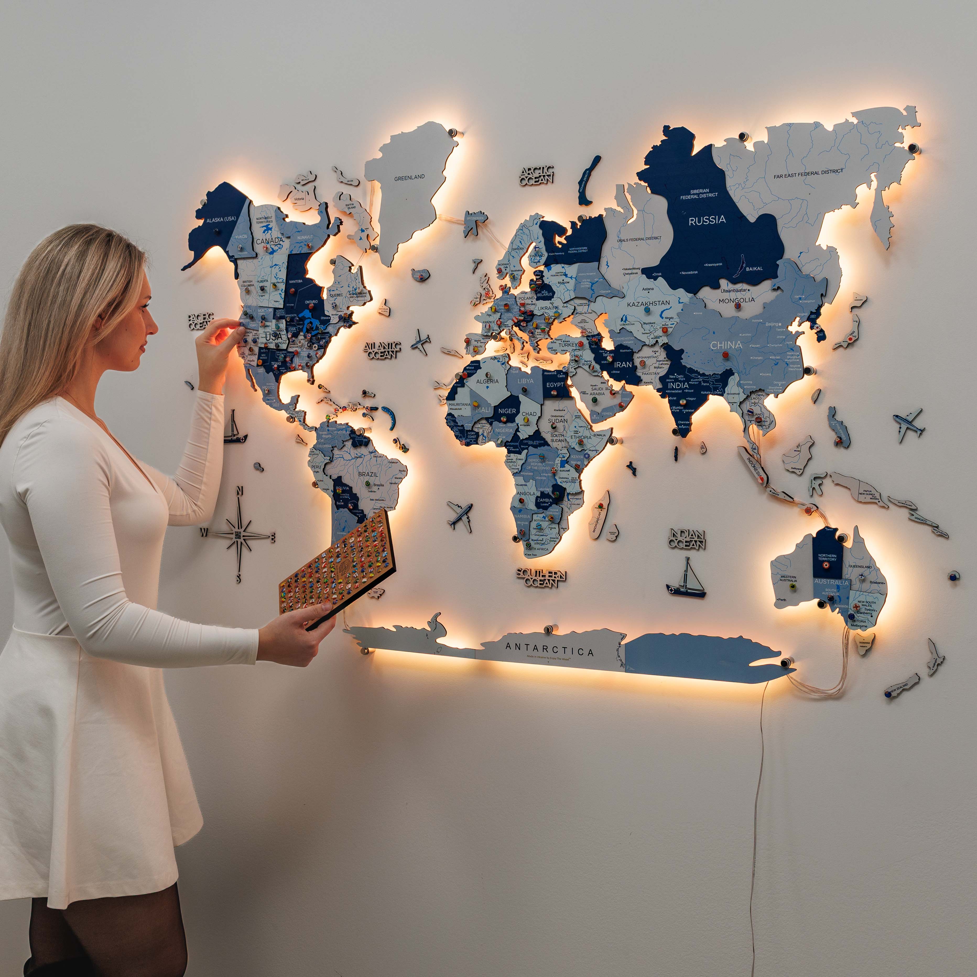 Woman assembling a world map puzzle on a wall with illuminated edges