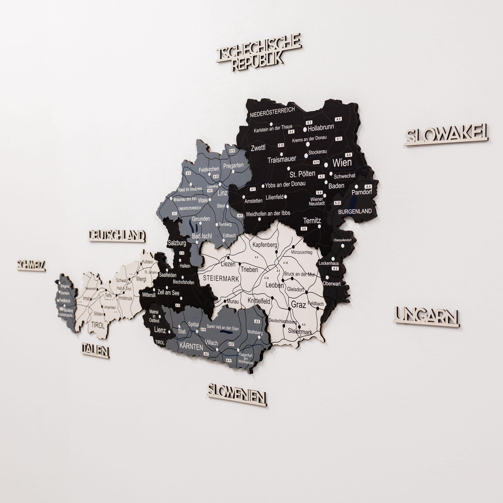 Wooden map of Austria with city names on a white background