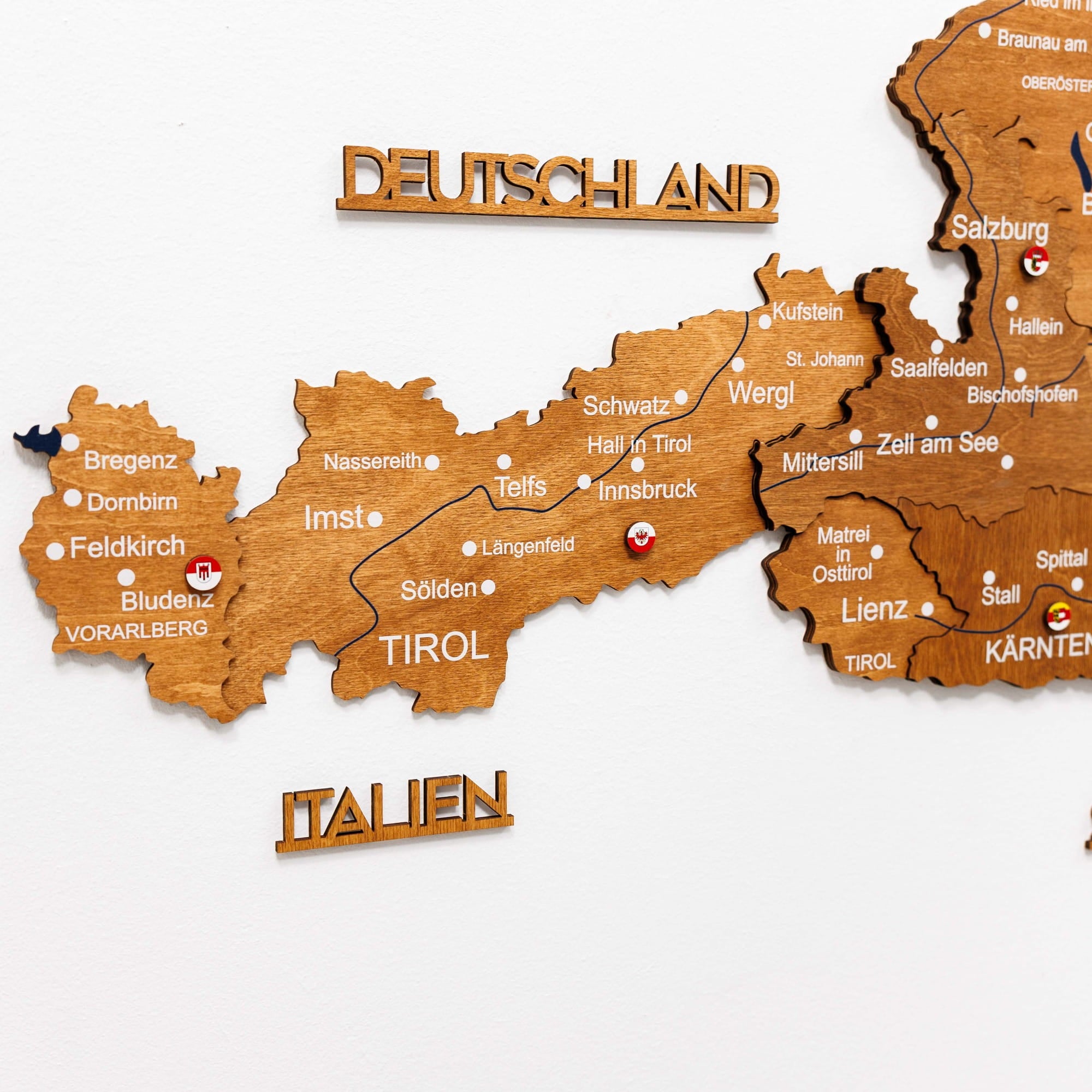Wooden map of Austria and Germany with city names labeled on a white background
