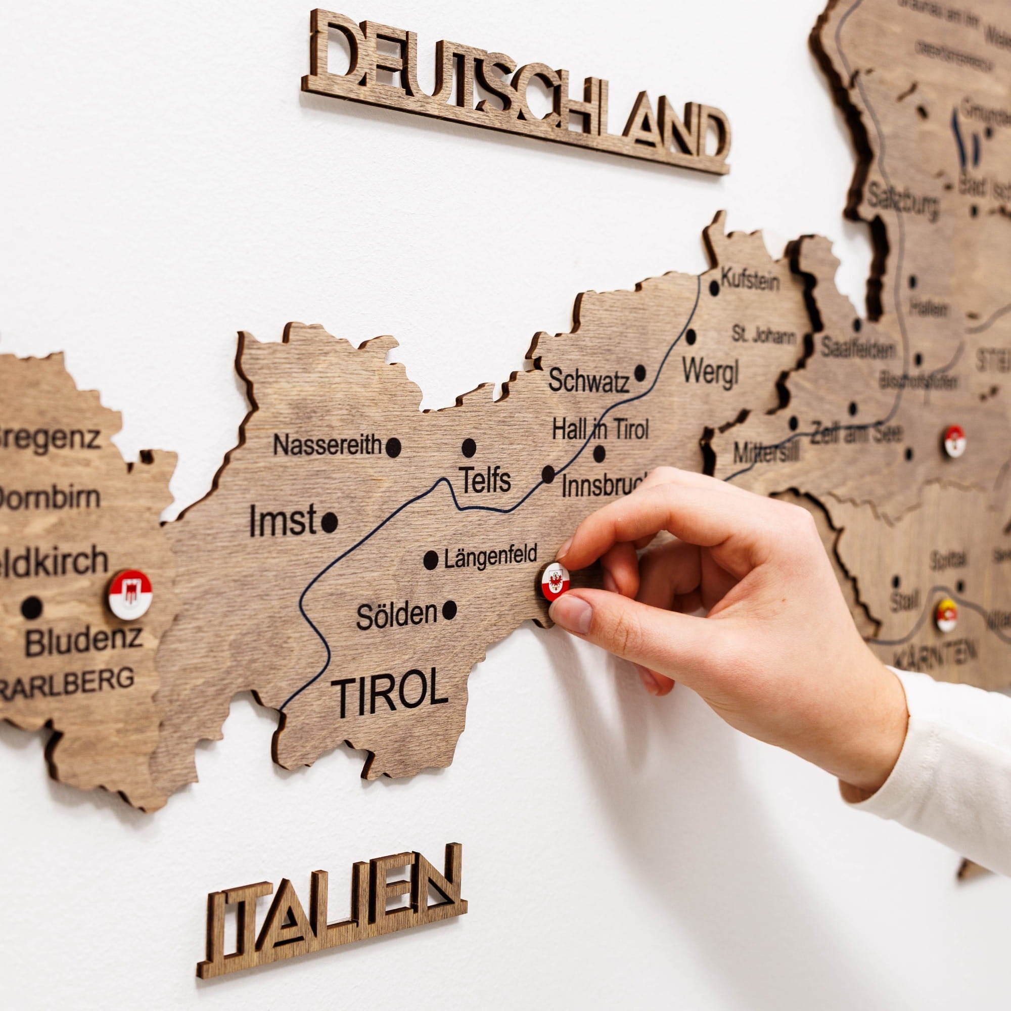 Wooden map of Germany and Italy with a hand pointing to a location.