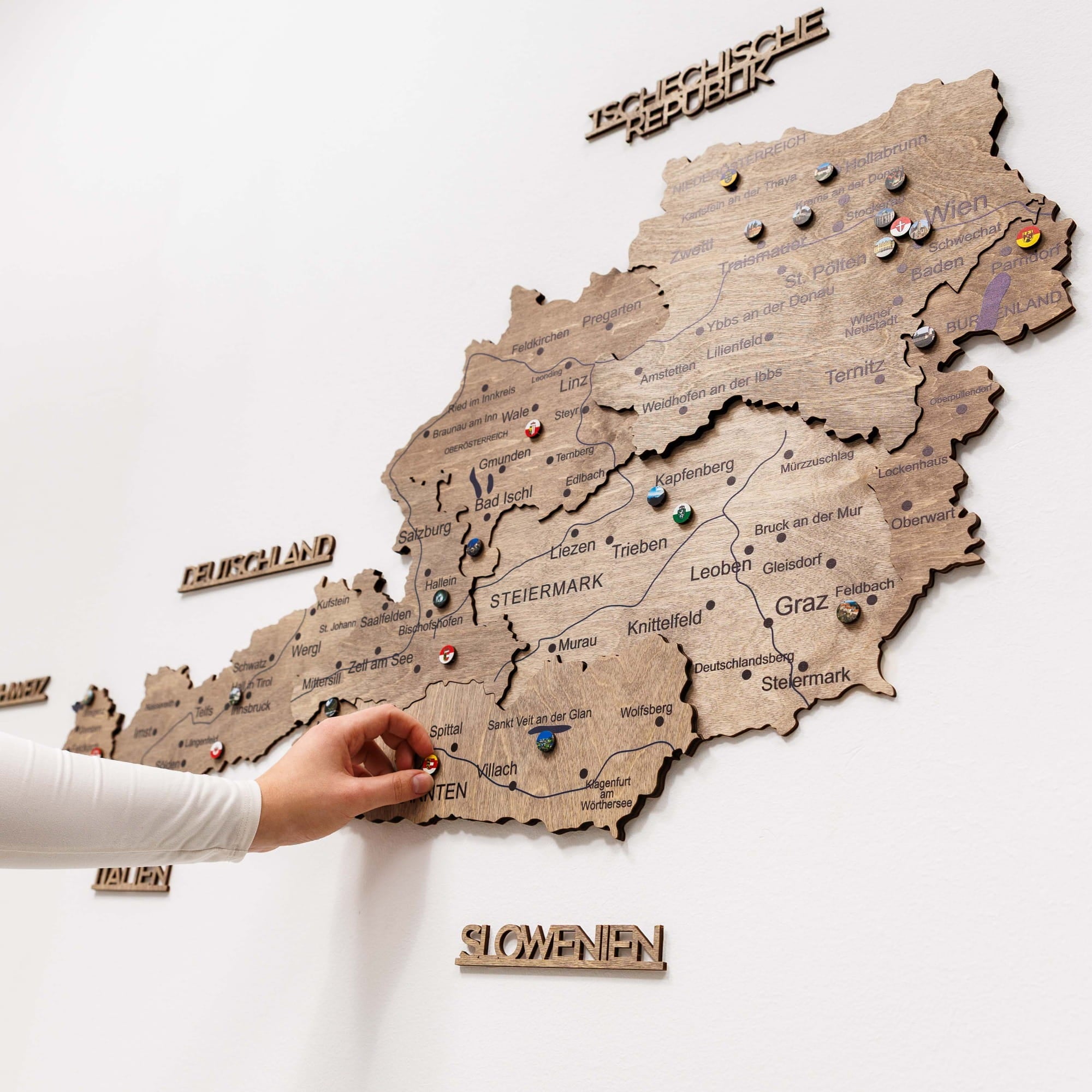 Wooden map of Austria with pins on a white wall