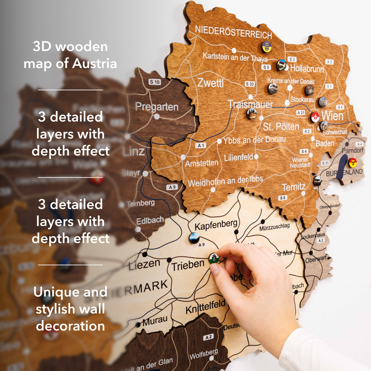 3D wooden map of Austria with a hand pointing to a location, text describing features.