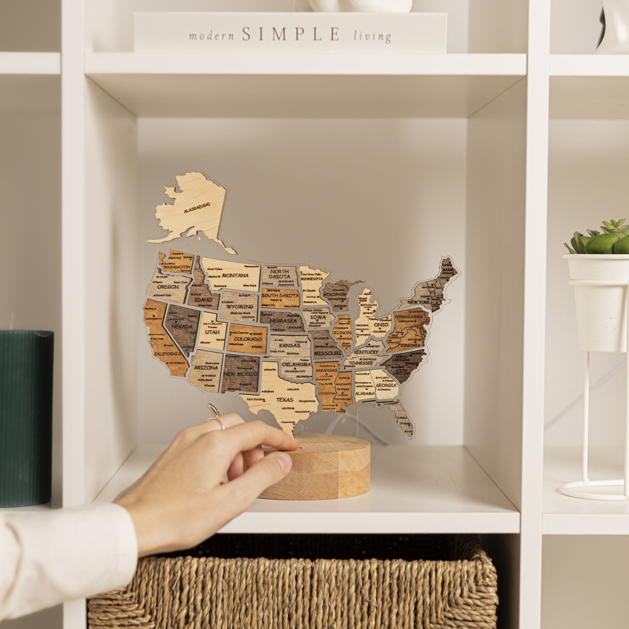 Wooden map of the United States on a shelf with a hand reaching towards it