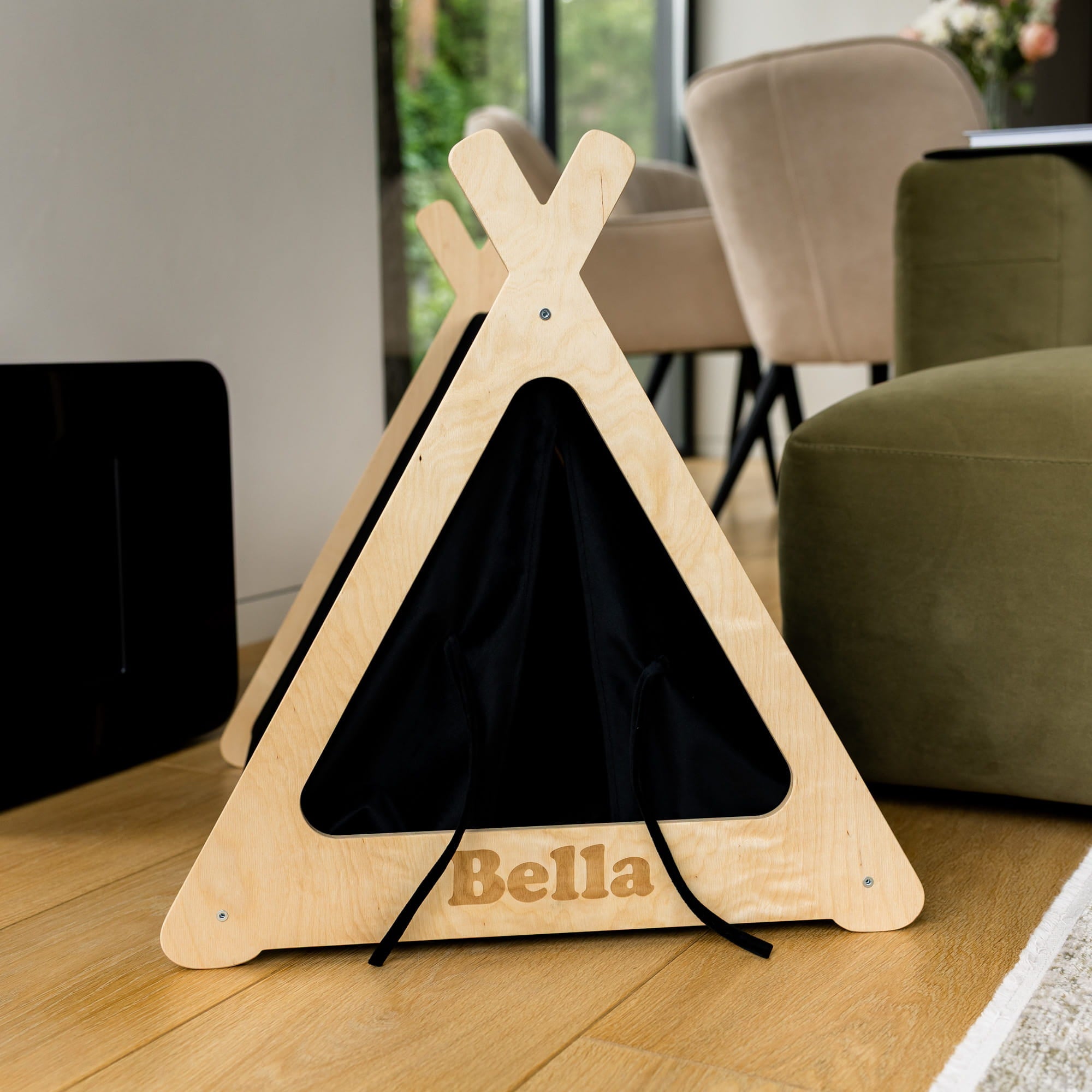 Wooden pet teepee with a black interior on a wooden floor, labeled 'Bella'.