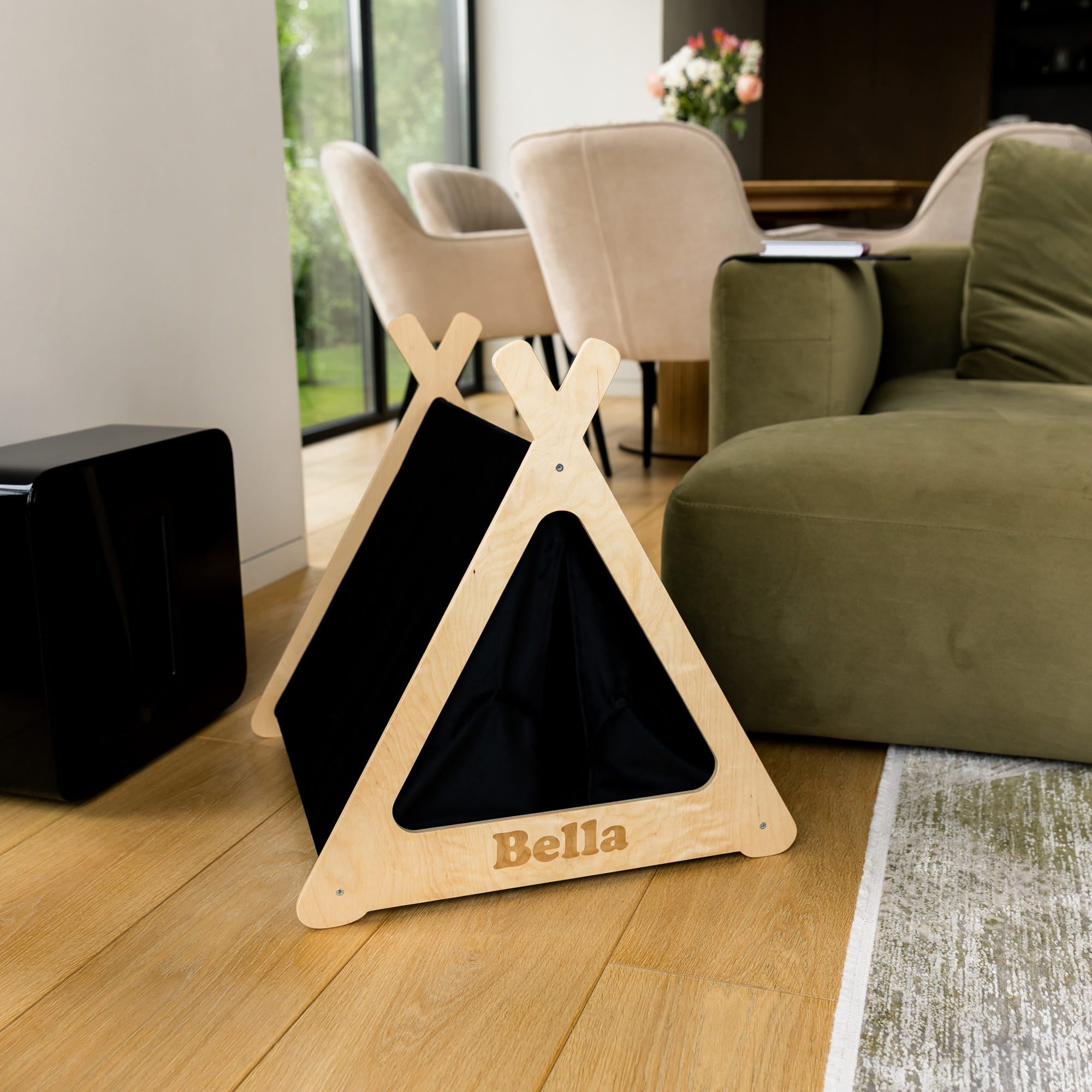 Wooden pet teepee with black interior and 'Bella' branding on a wooden floor.