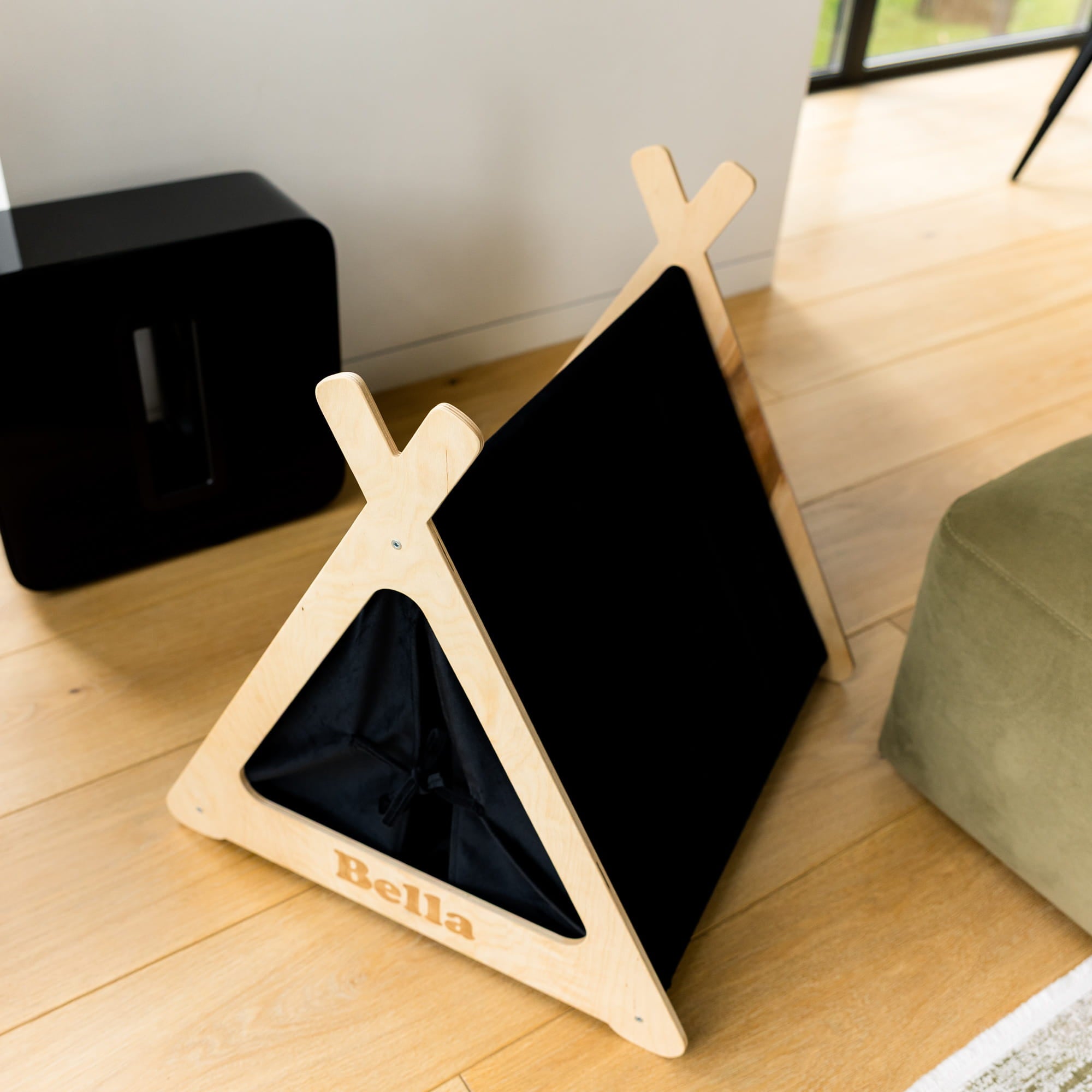 Wooden pet teepee with a black interior on a wooden floor.