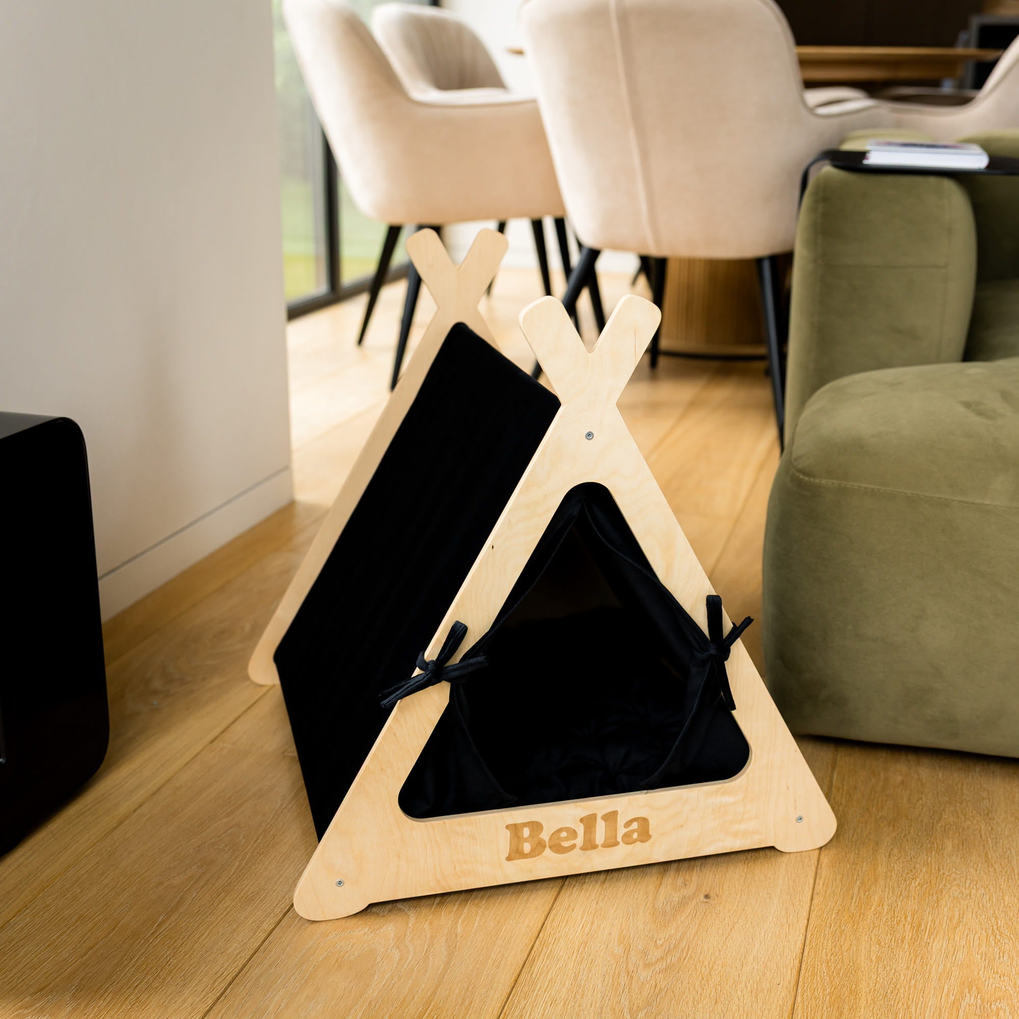 Pet teepee with black interior and 'Bella' branding on a wooden floor.