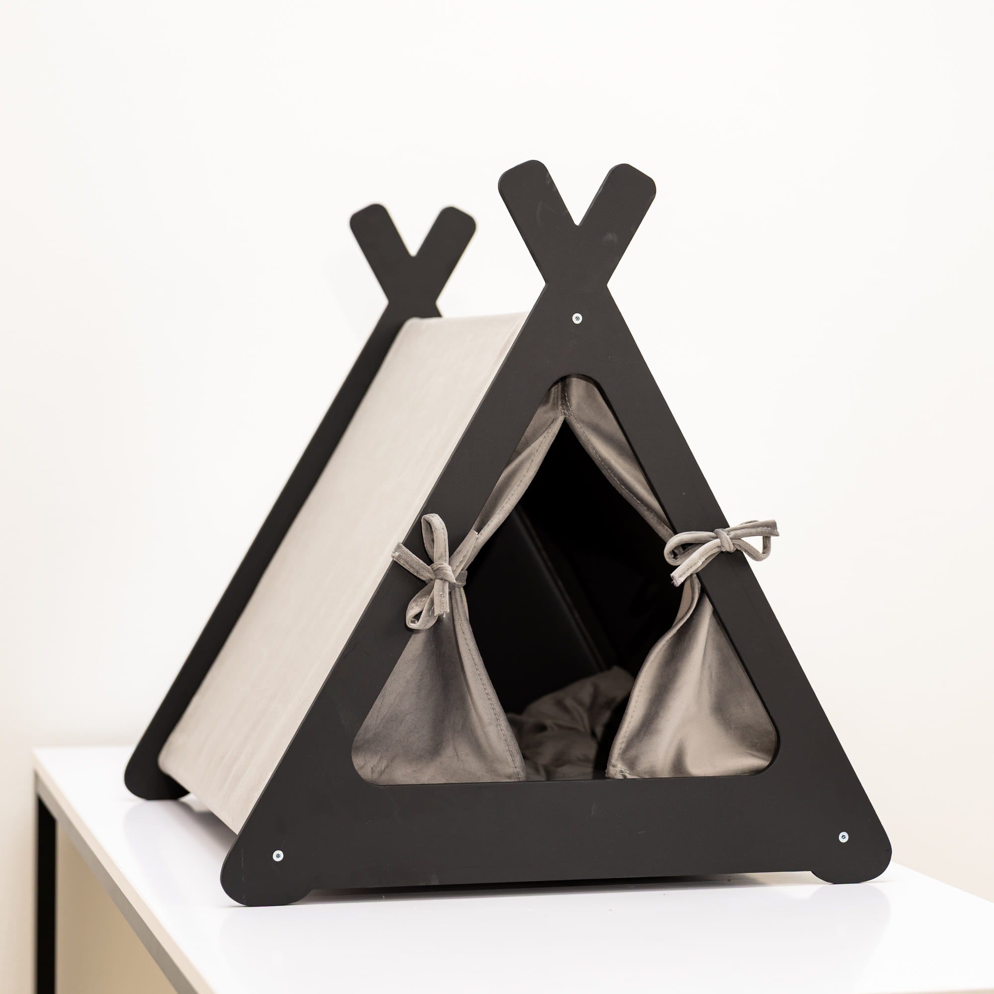 Black pet teepee on a white surface with a neutral background