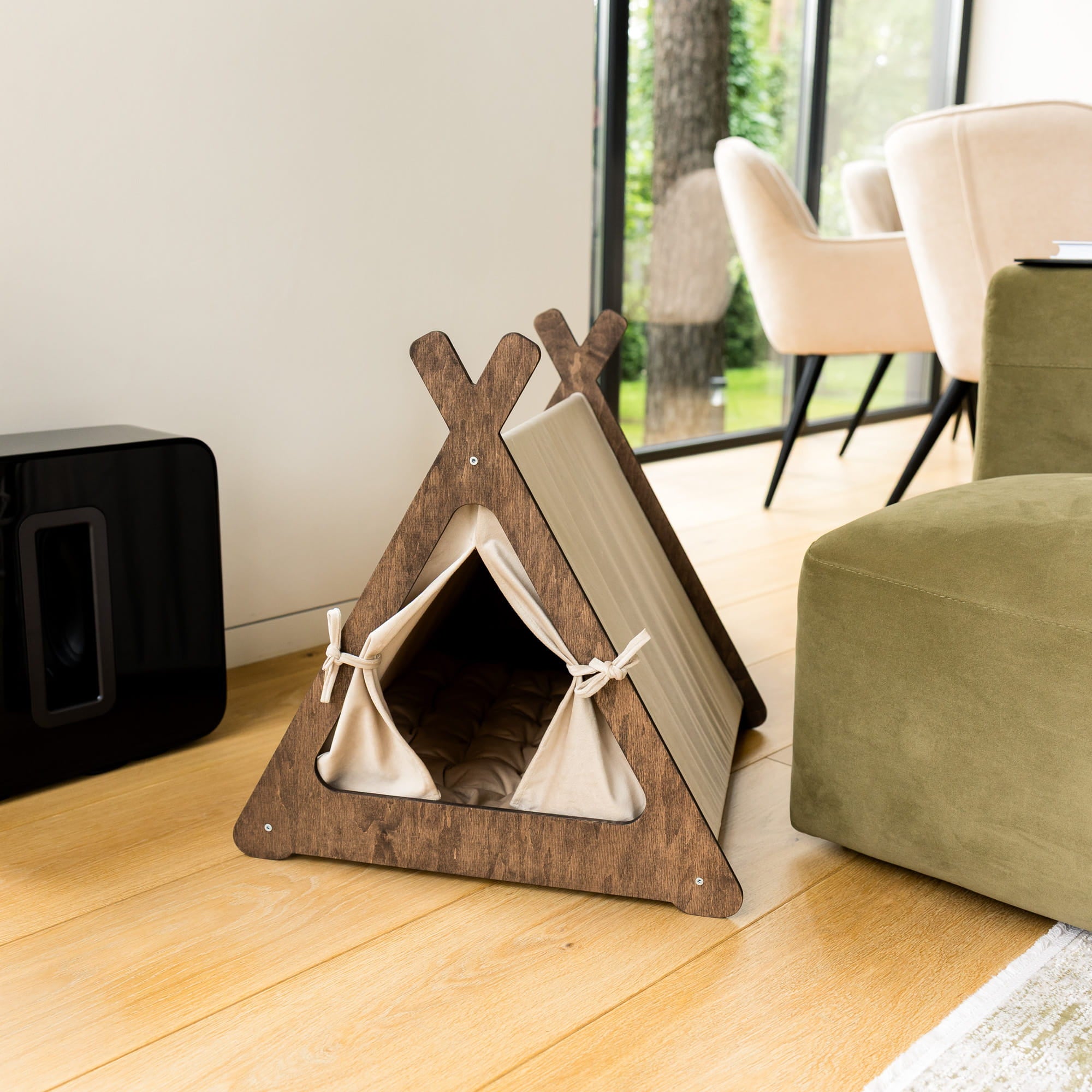 Wooden pet teepee with a cushion on a wooden floor in a room with furniture.