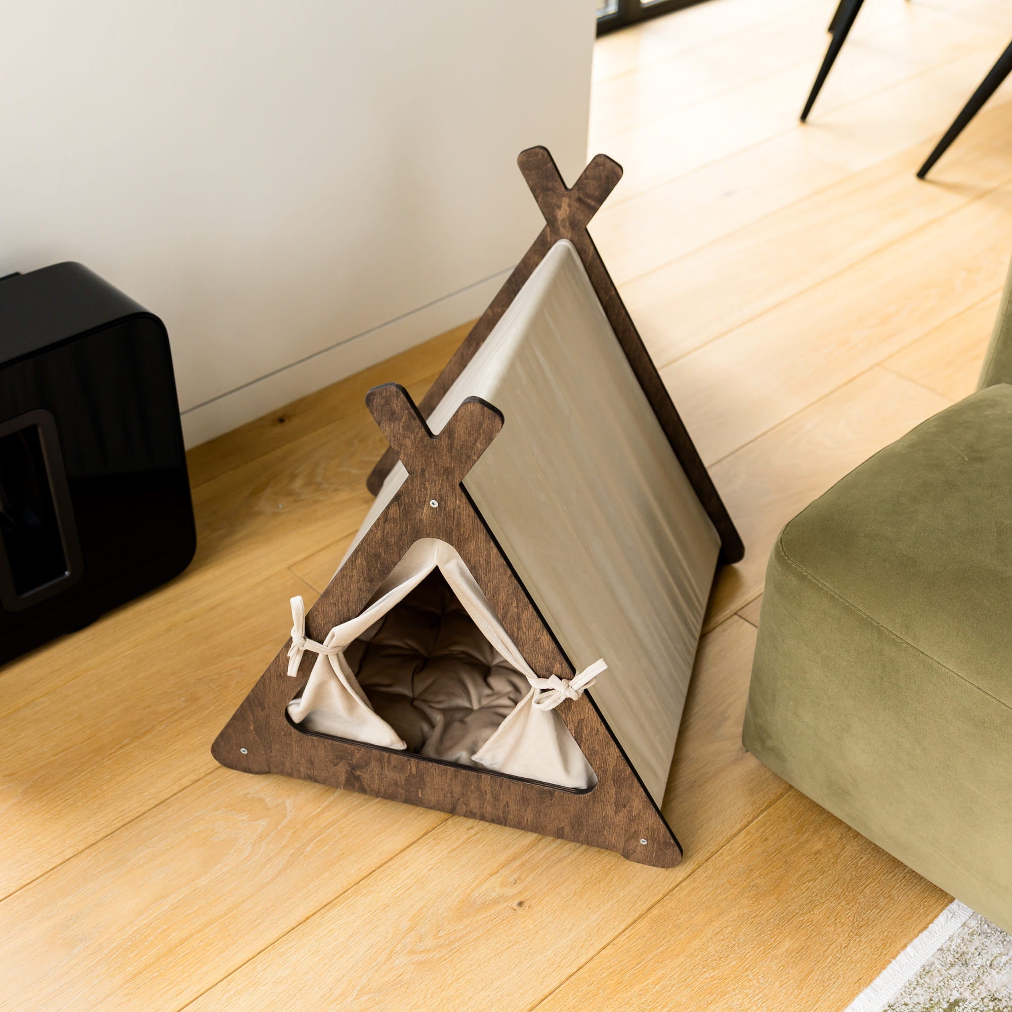 Pet teepee on a wooden floor next to a green cushion