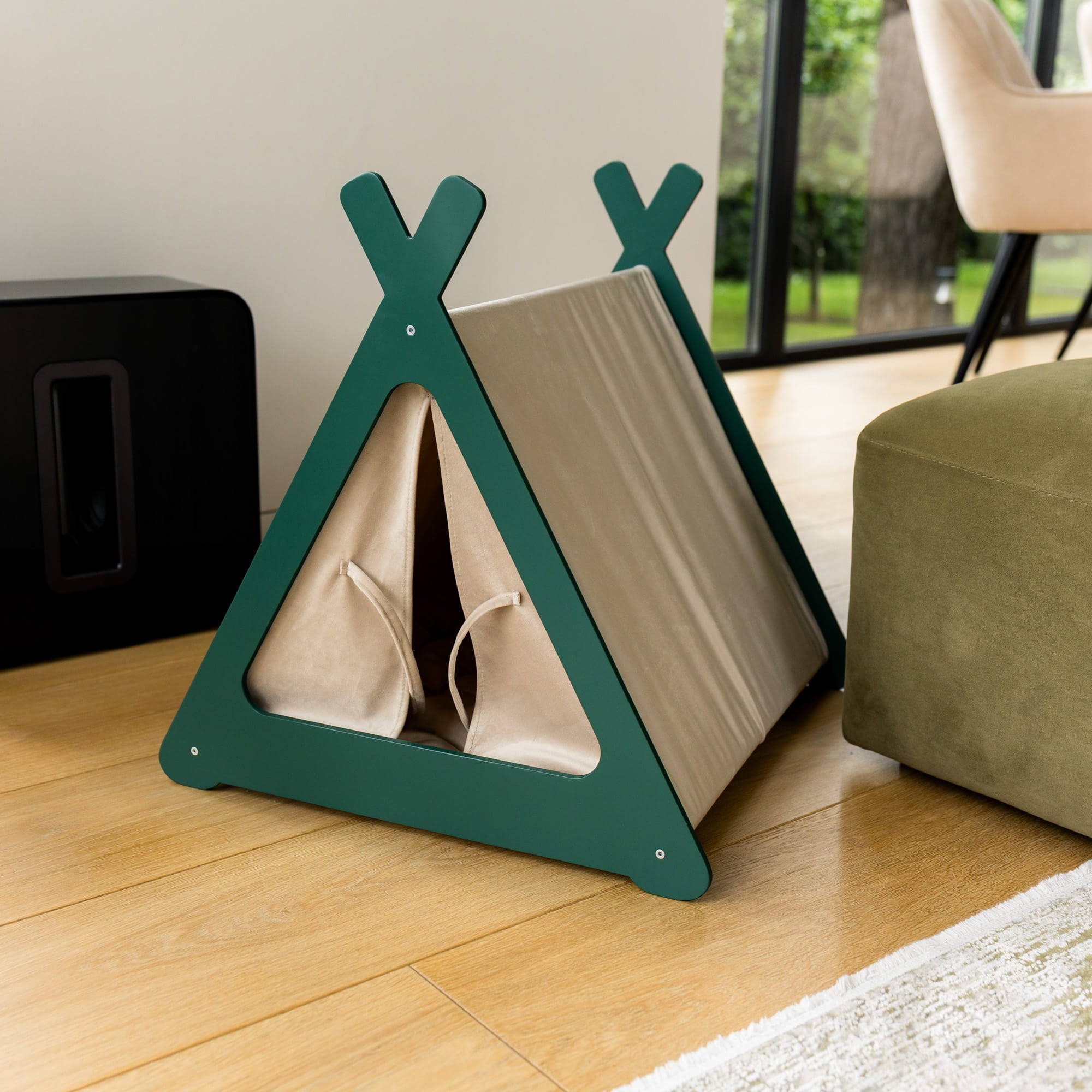 Pet teepee with green frame and beige interior on a wooden floor.