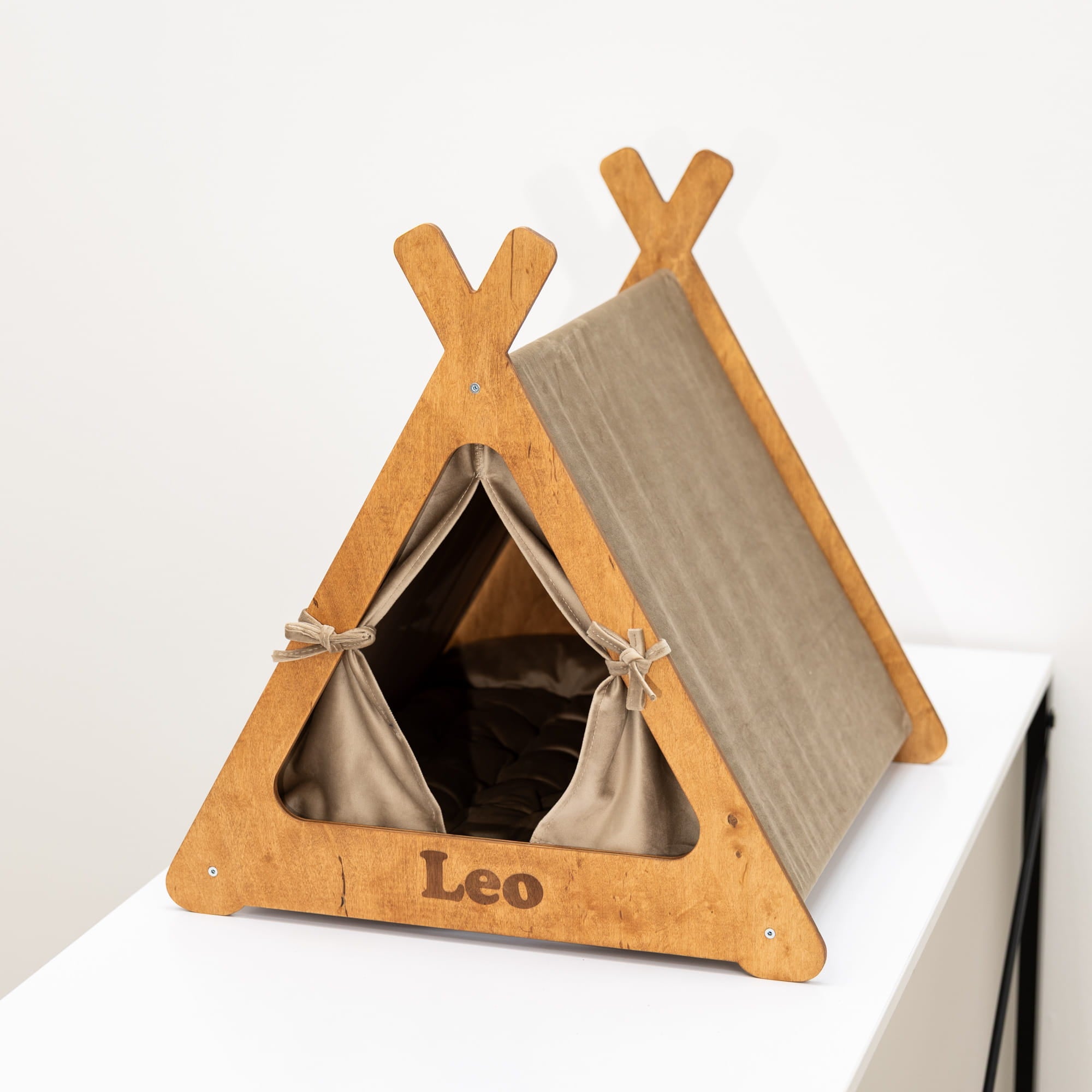 Pet teepee with wooden frame and brown fabric interior on a white background