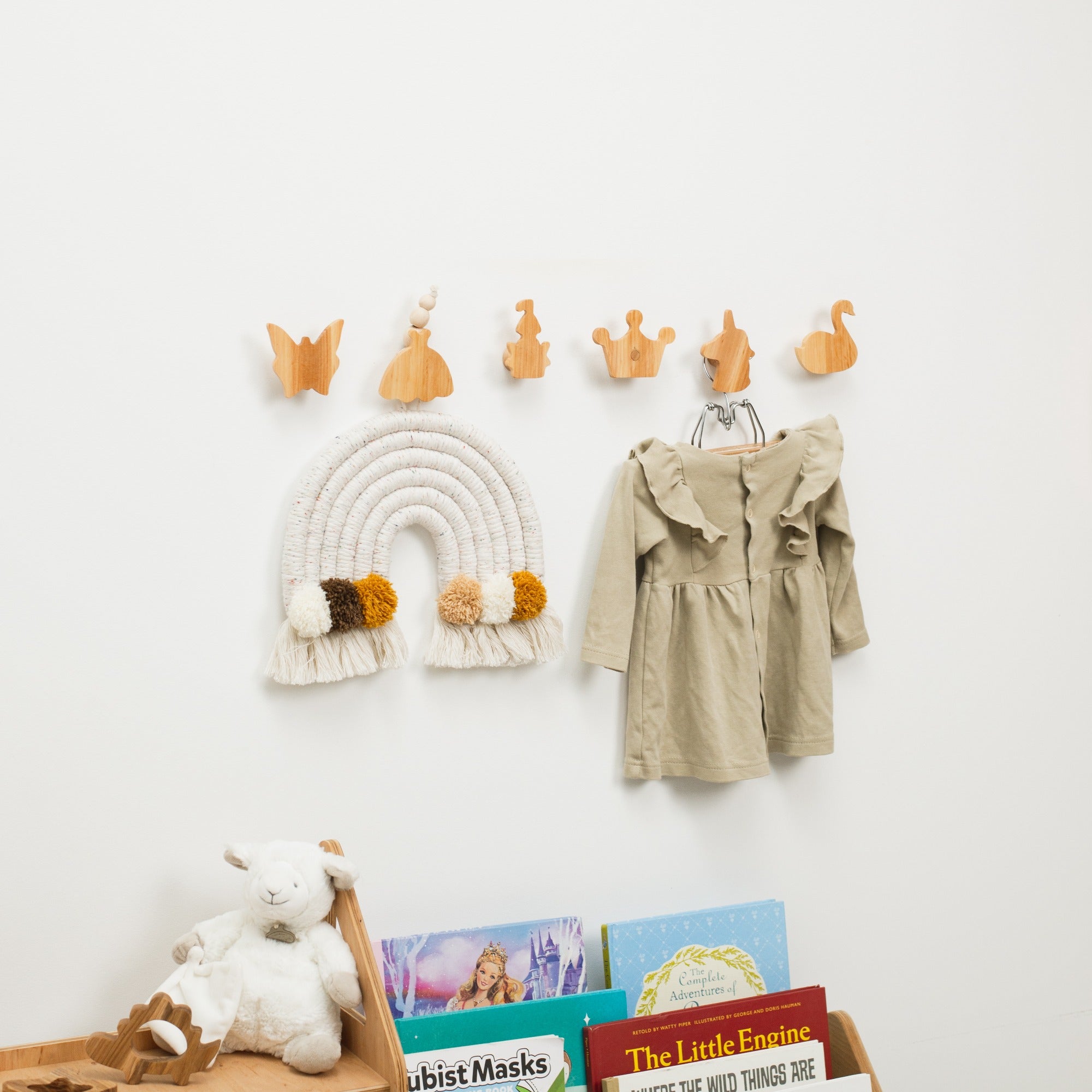 Children's room with wooden hooks on the wall, a coat, books, and toys.