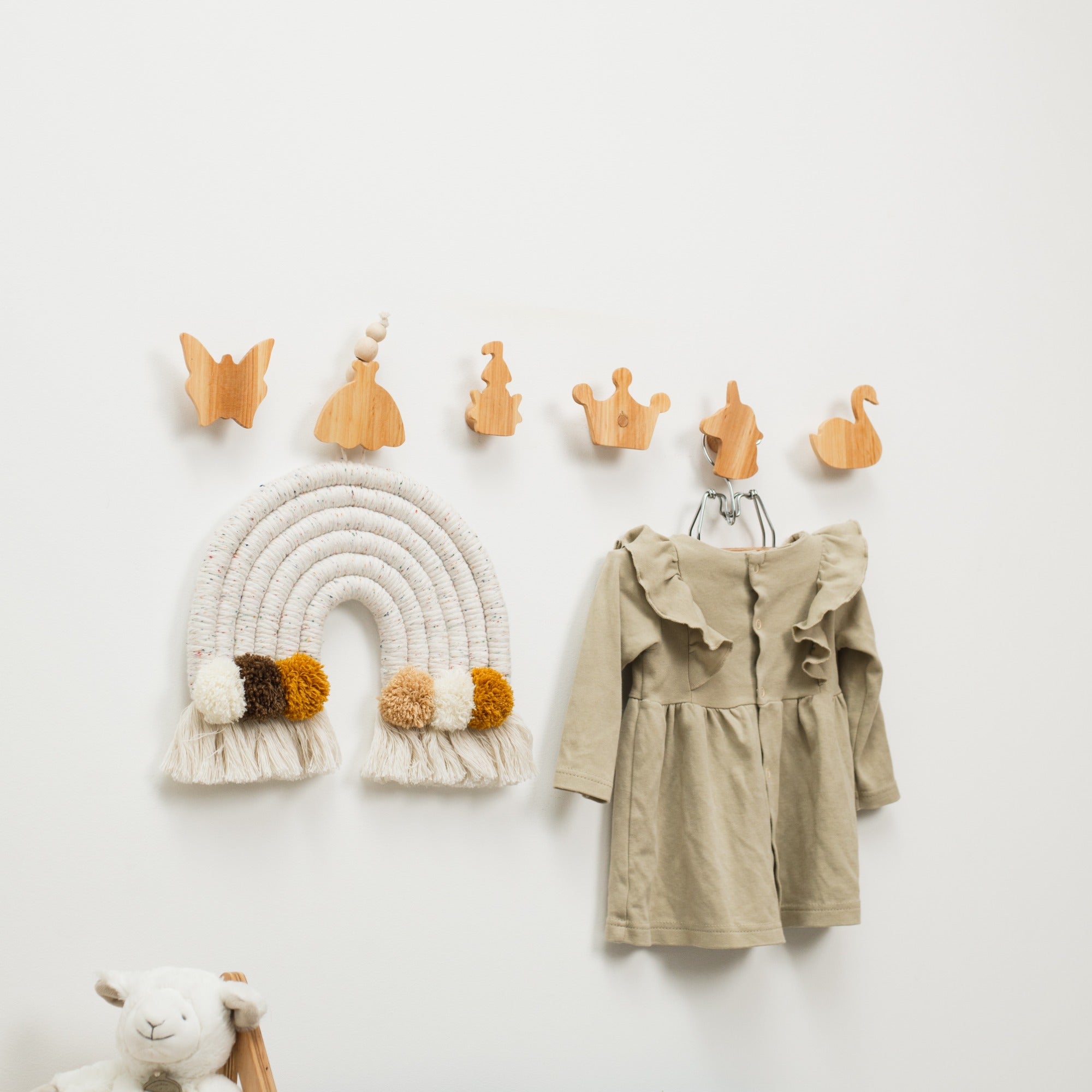 Wooden hooks on a white wall with a child's coat and decorative items.