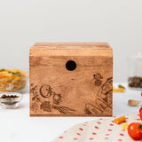 A wooden recipe box with pepper illustrations on the lid, displayed on a kitchen counter surrounded by recipe cards and ingredients.