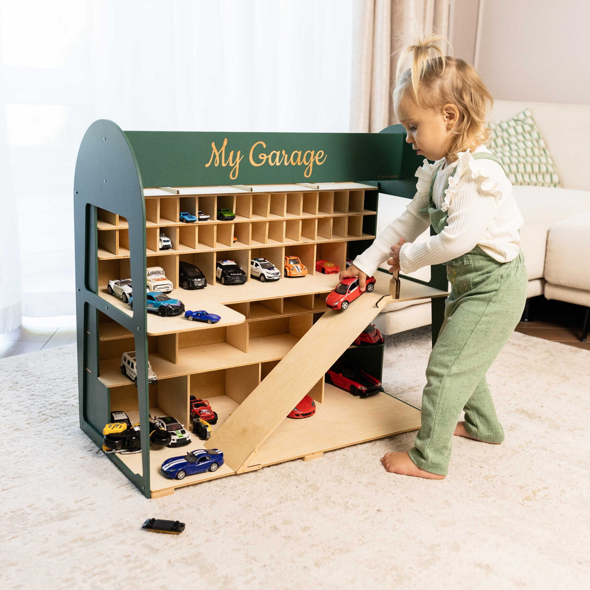 The playset has multiple storage cubbies, a ramp, and several toy cars, with the words "My Garage" painted on the front.