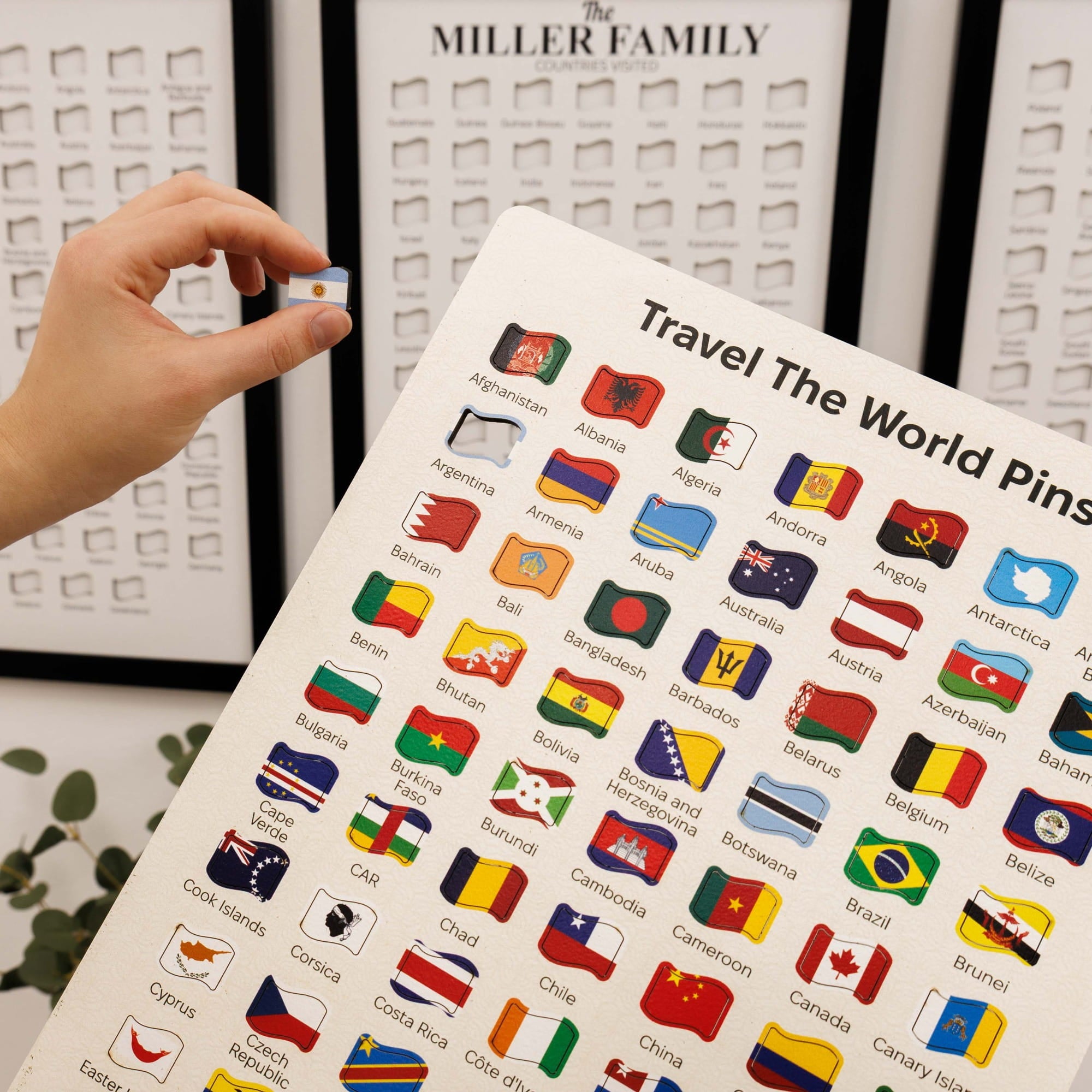 Sheet of travel-themed pins with various country flags, held by a hand.