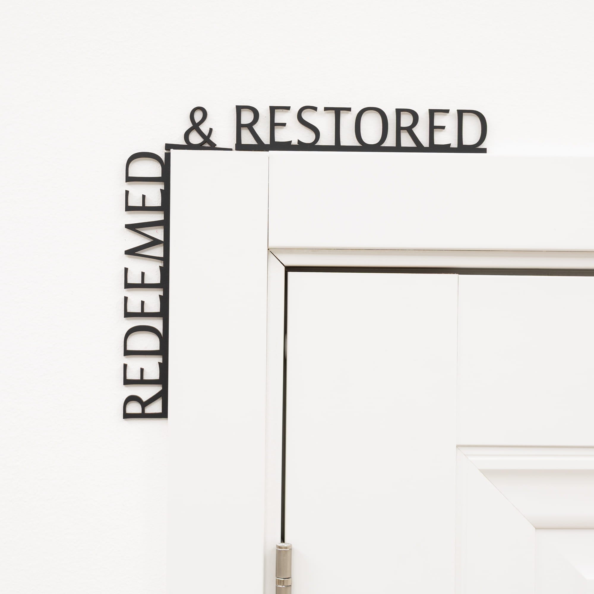 Decorative wall art with 'REDEEMED & RESTORED' text on a white background