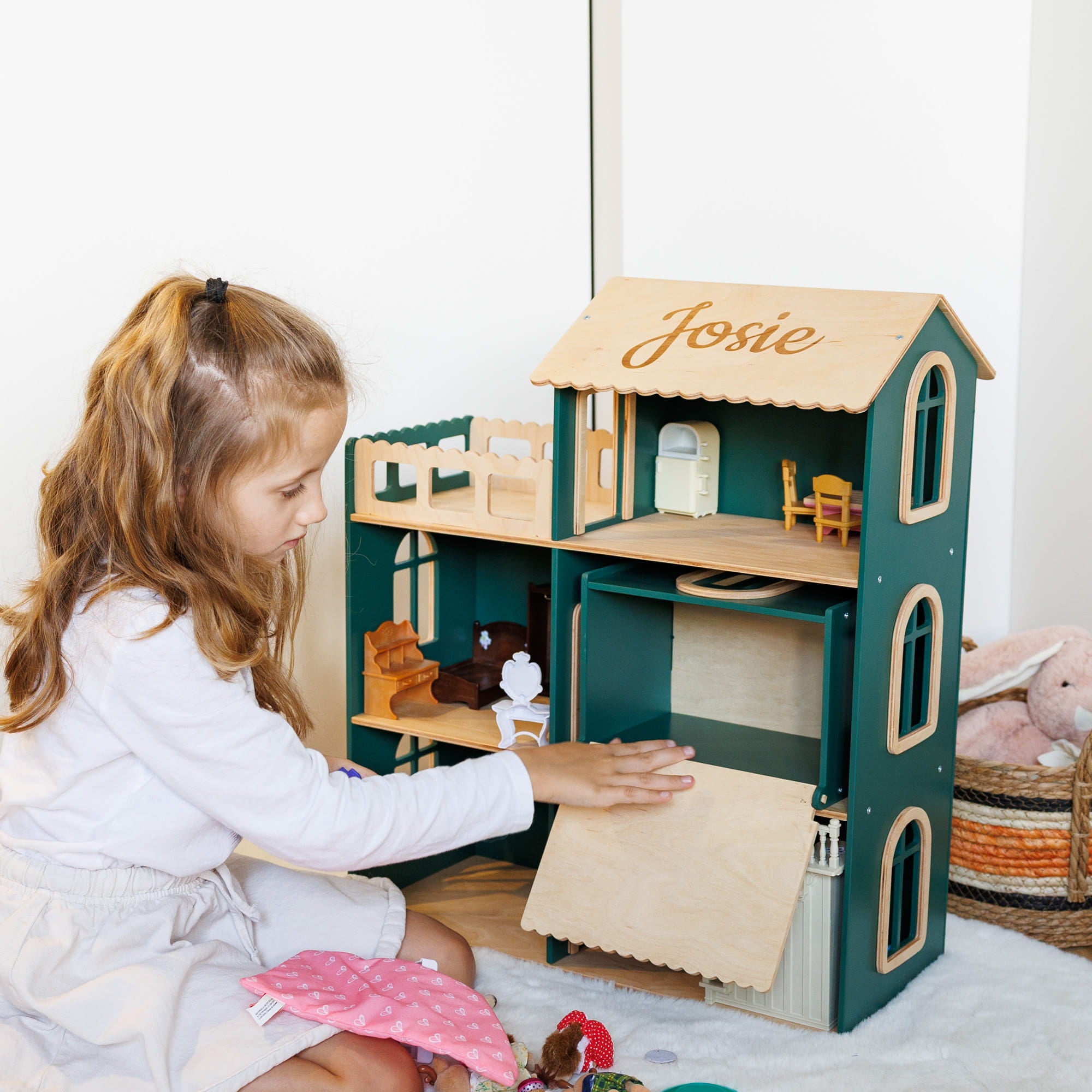 The dollhouse is made of dark green and natural light wood,