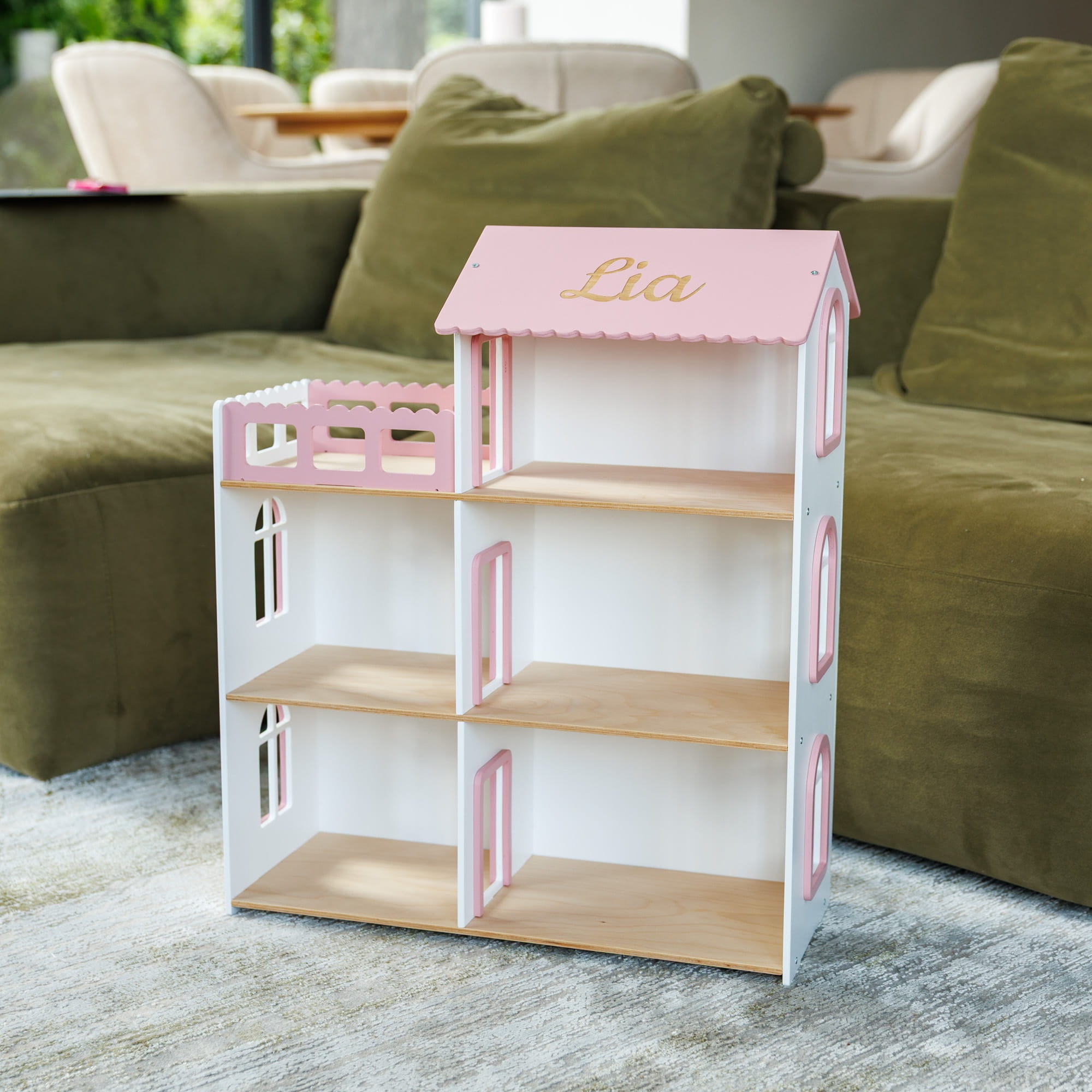 A white wooden dollhouse with pink trim and light wood shelves