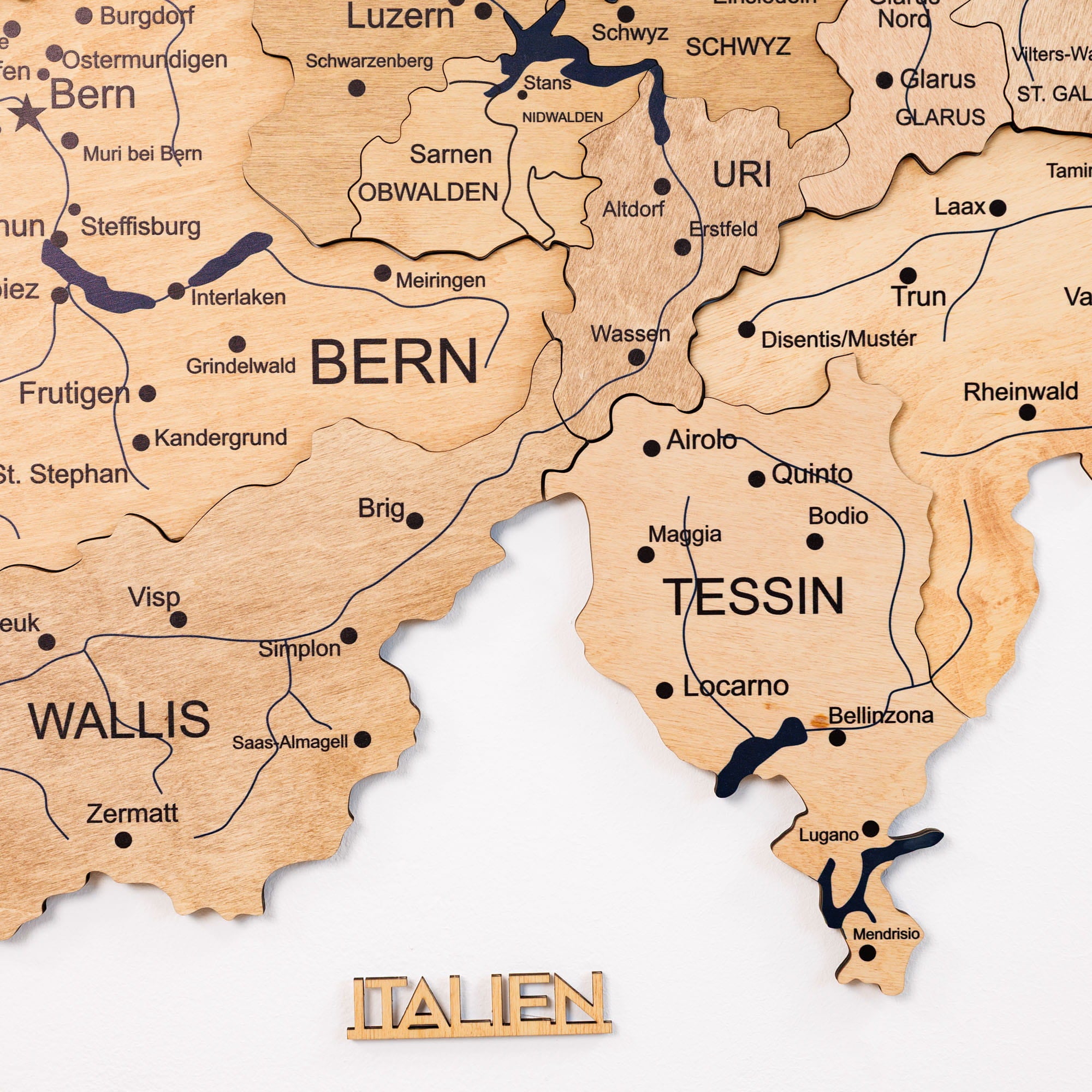 Wooden map of Switzerland with cities labeled on a white background