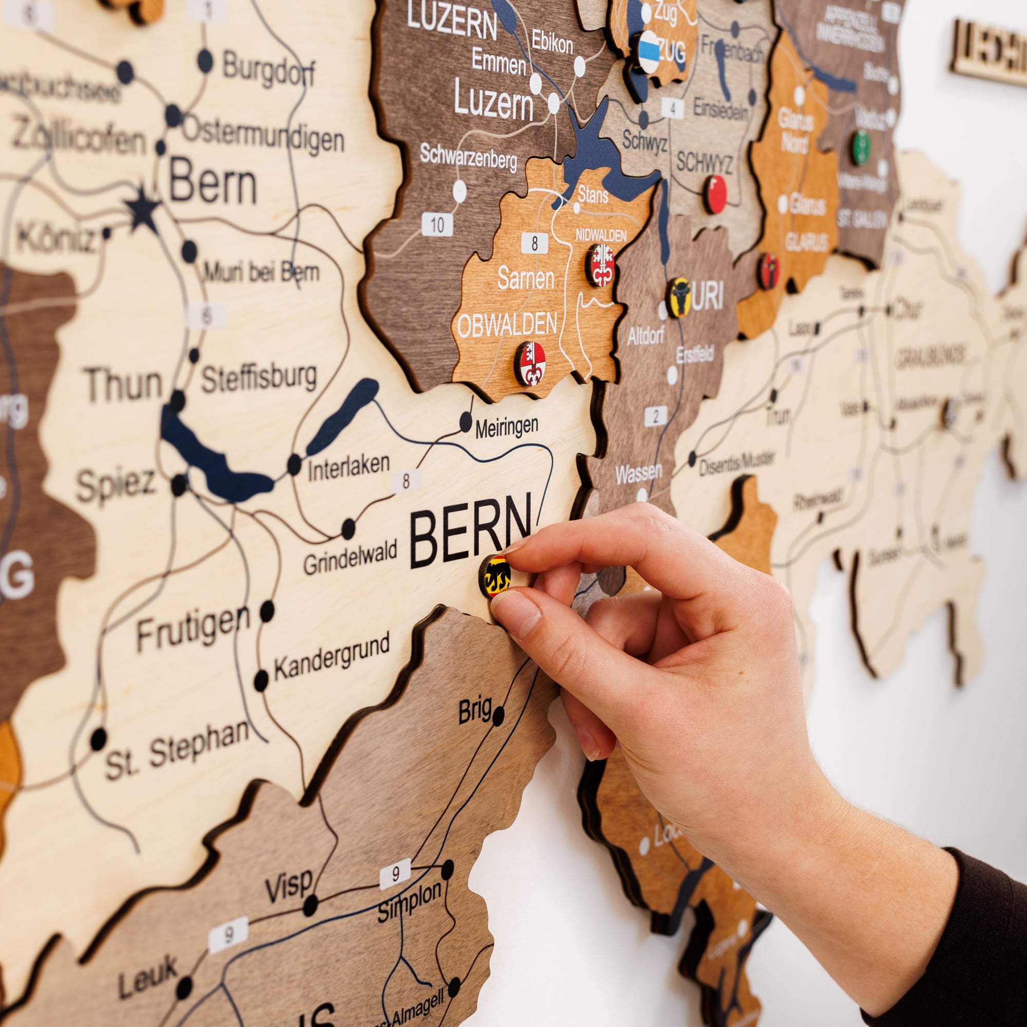 Wooden map of Switzerland with a hand pointing to Bern