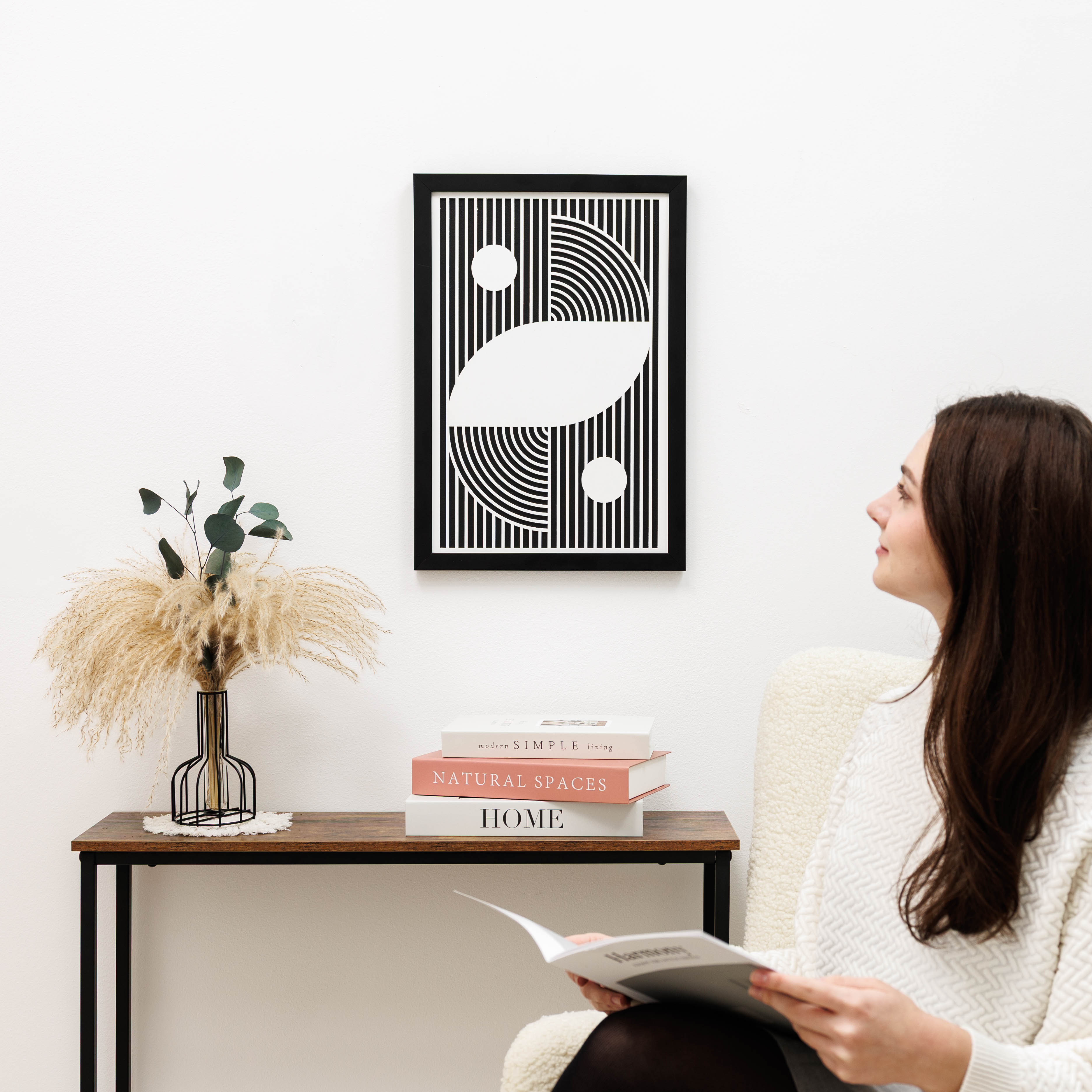 Woman reading a book in a cozy room with abstract art and decor.