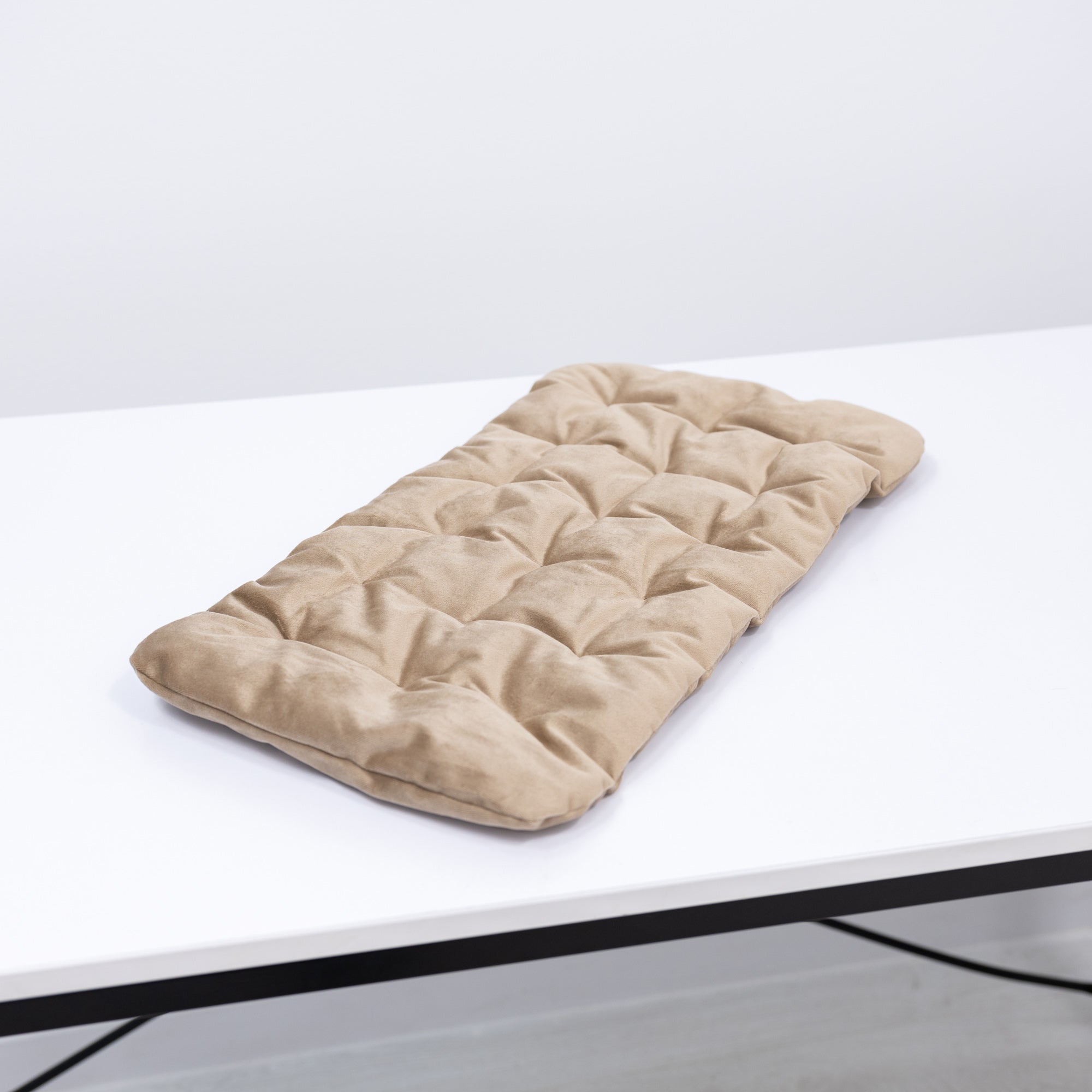 Beige quilted mat on a white surface with a light gray background