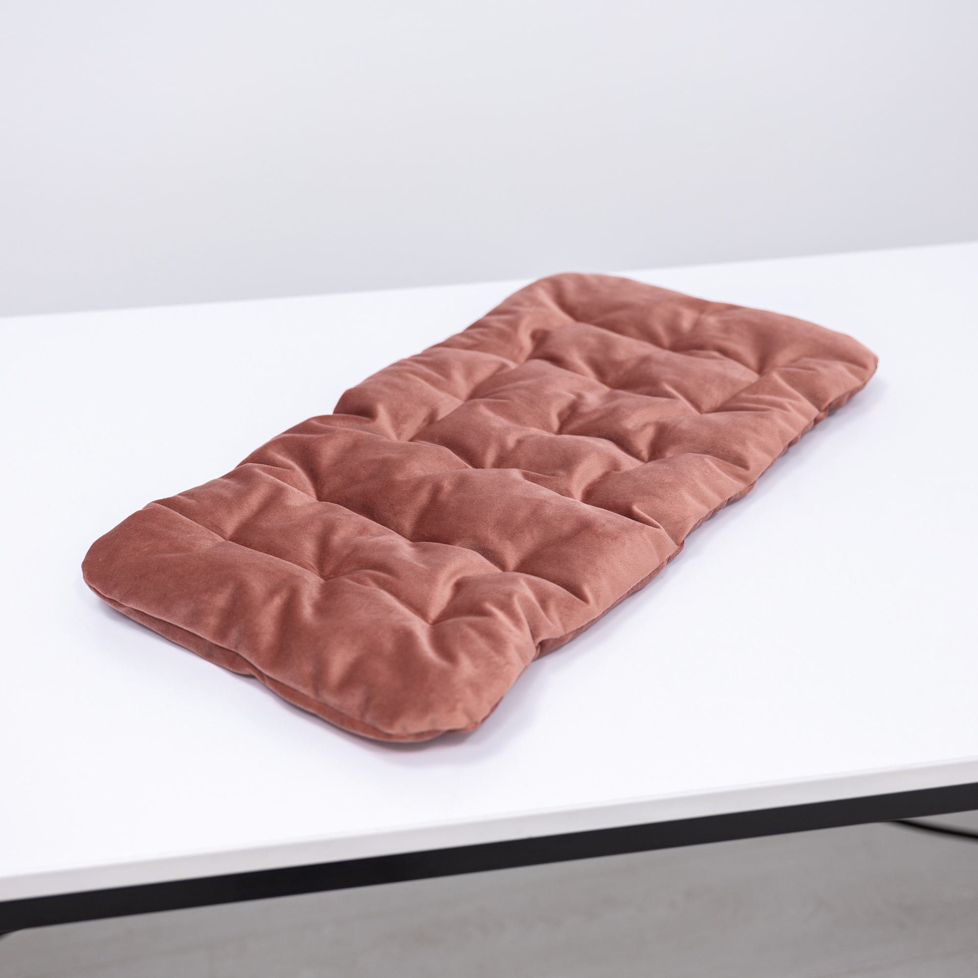 Pink quilted mat on a white surface with a light gray background