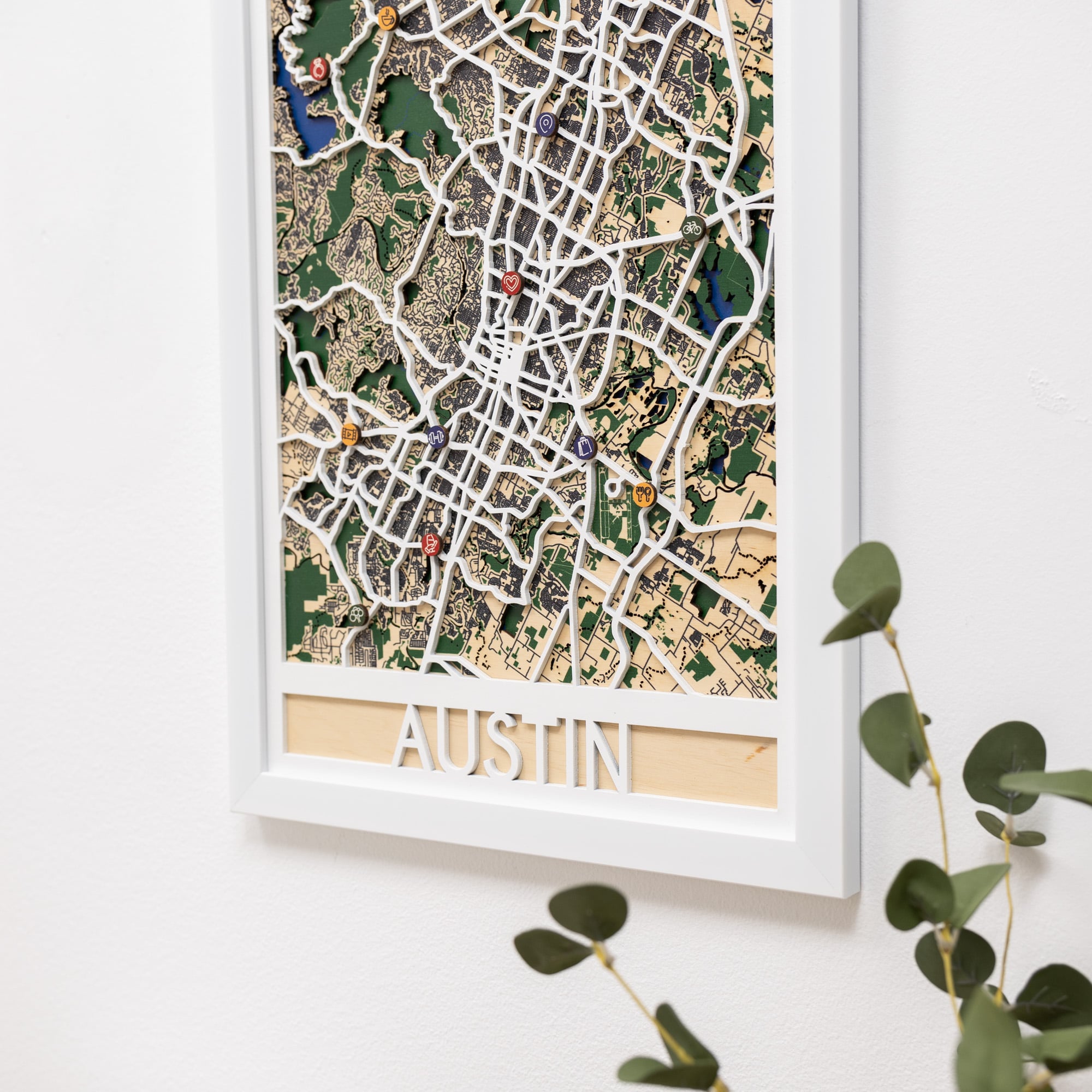 Framed map of Austin with decorative pins on a white wall.