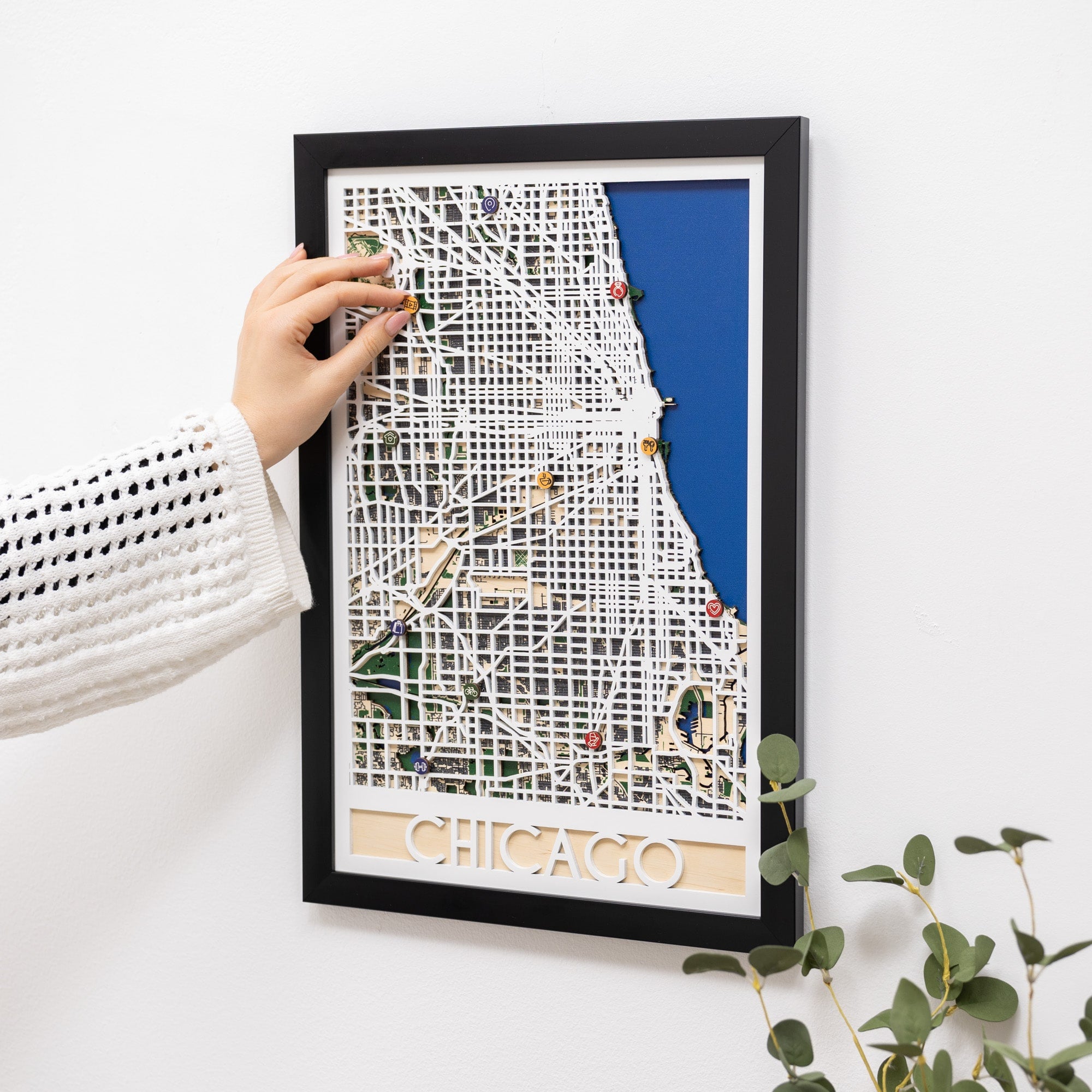 Framed map of Chicago with decorative pins on a white wall.