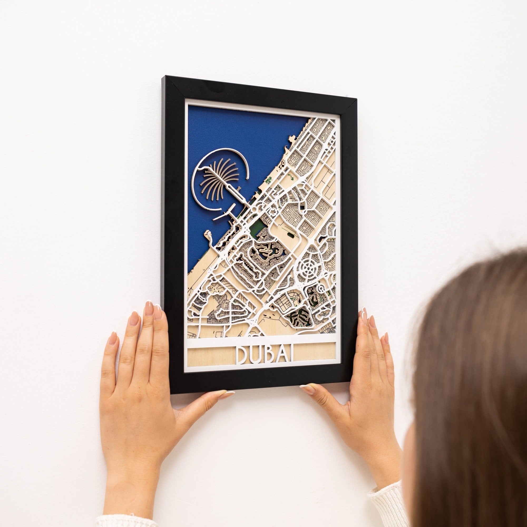 Framed map of Dubai held by a person on a white background